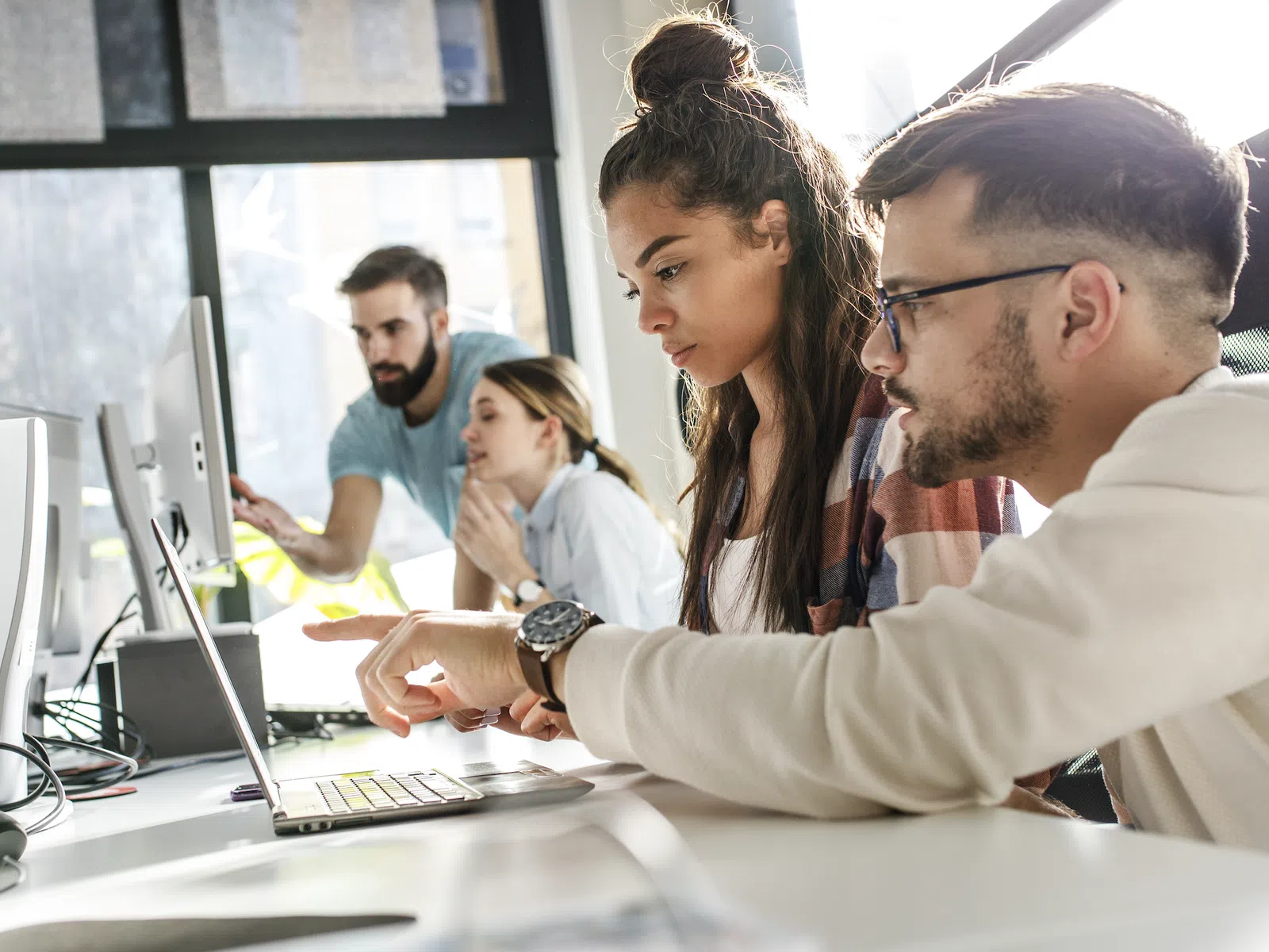 Young professionals collaborating and working together on computers in a bright modern office space.