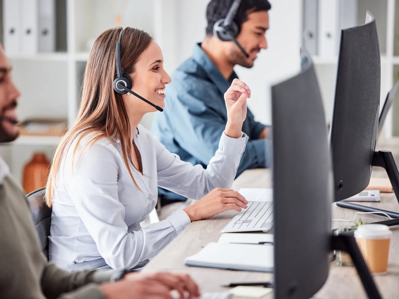 a woman wearing headphones and sitting at a desk with a man and a woman looking at a
