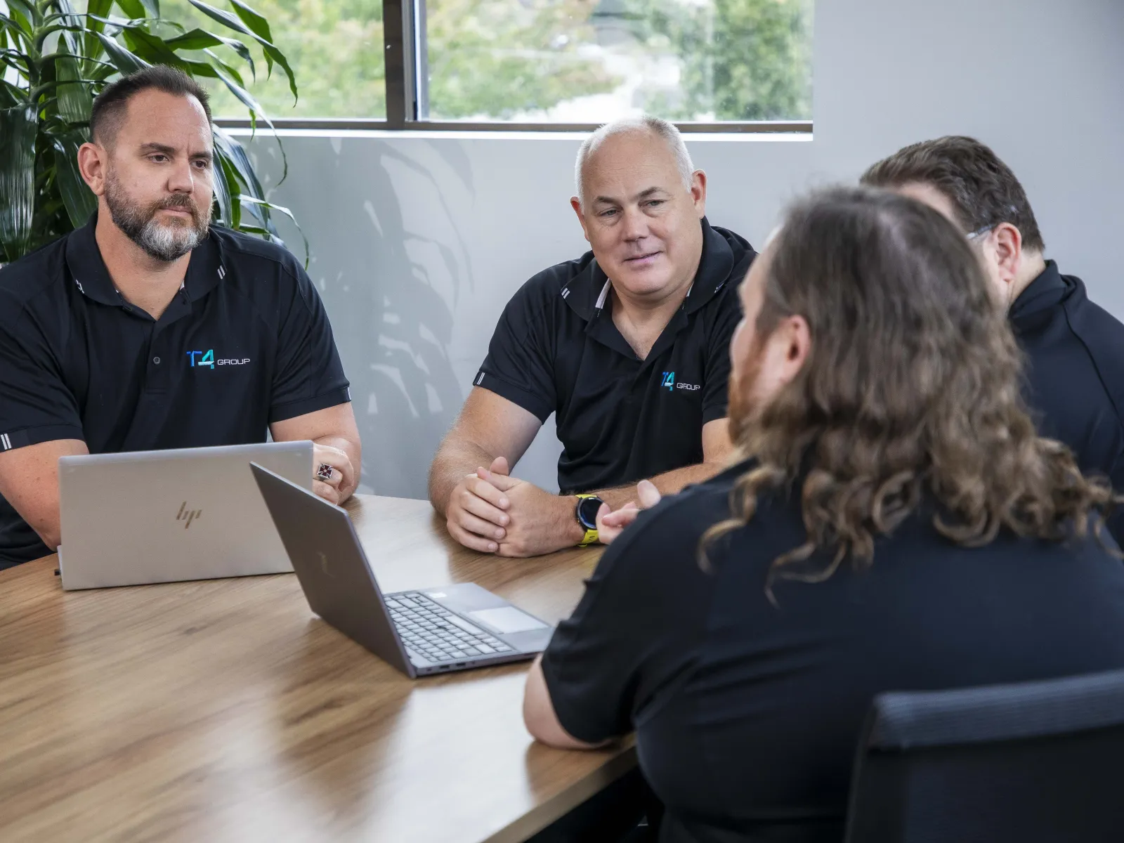a group of people sitting around a table looking at a laptop