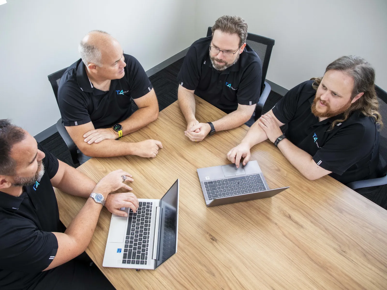 a group of people sitting around a table looking at a laptop