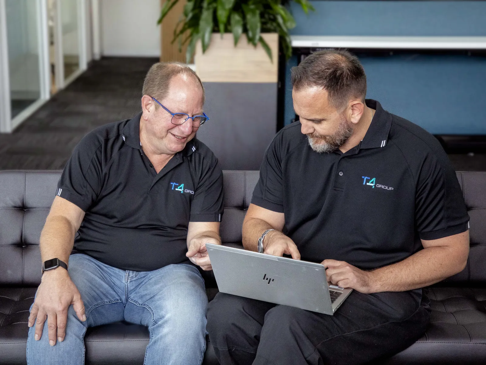 men sitting on a couch looking at a laptop
