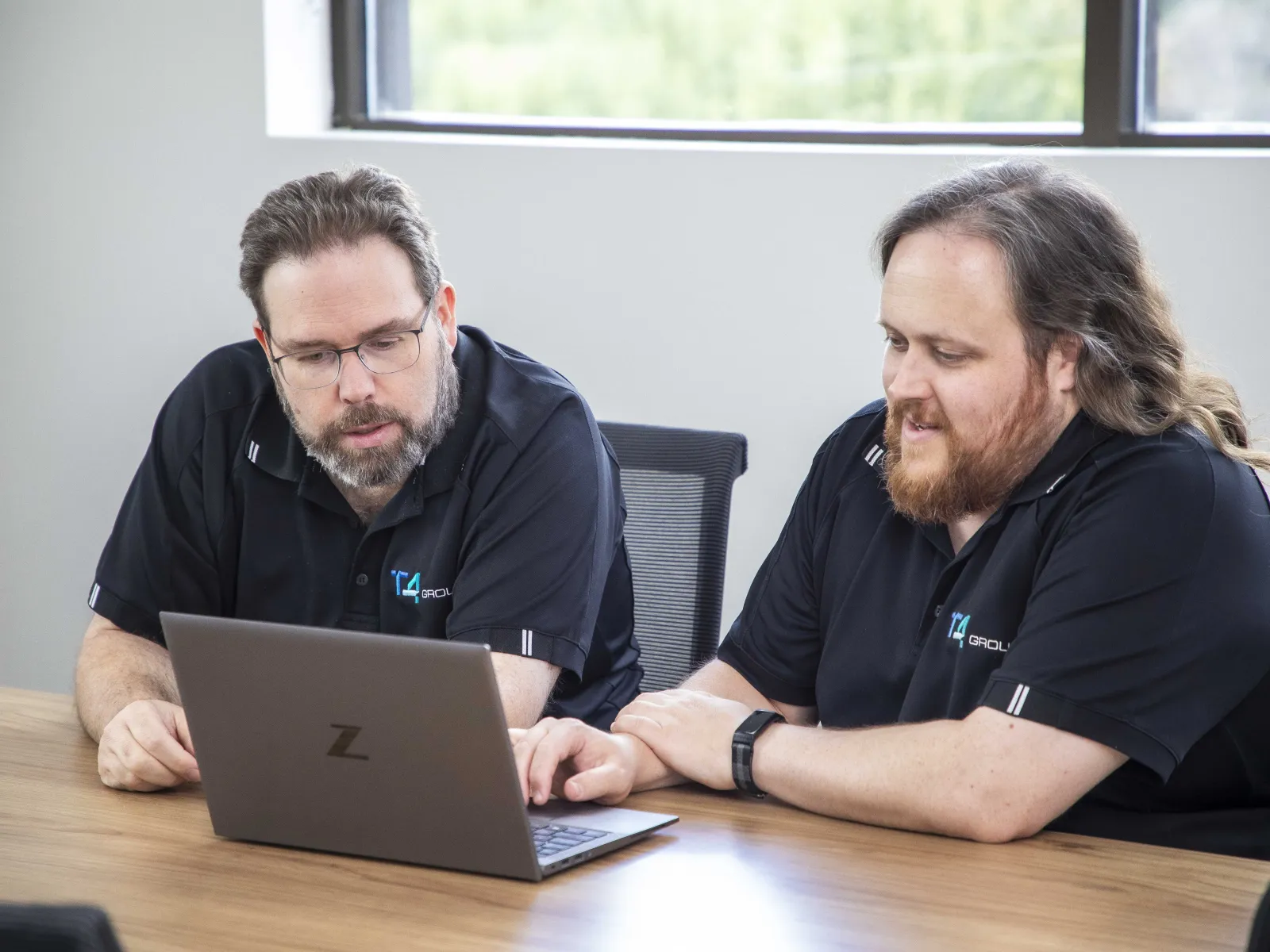 a couple of men looking at a laptop