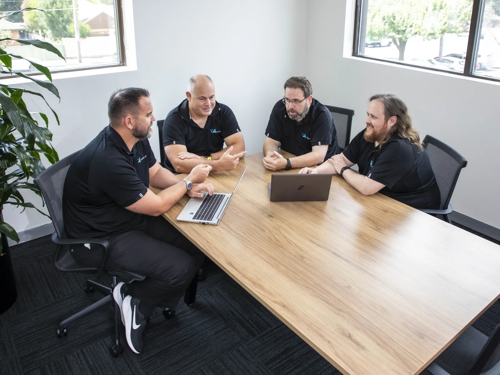 a group of people sitting around a table with laptops