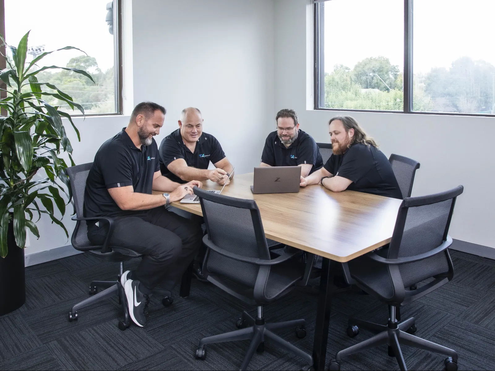 a group of people sitting around a table with a laptop