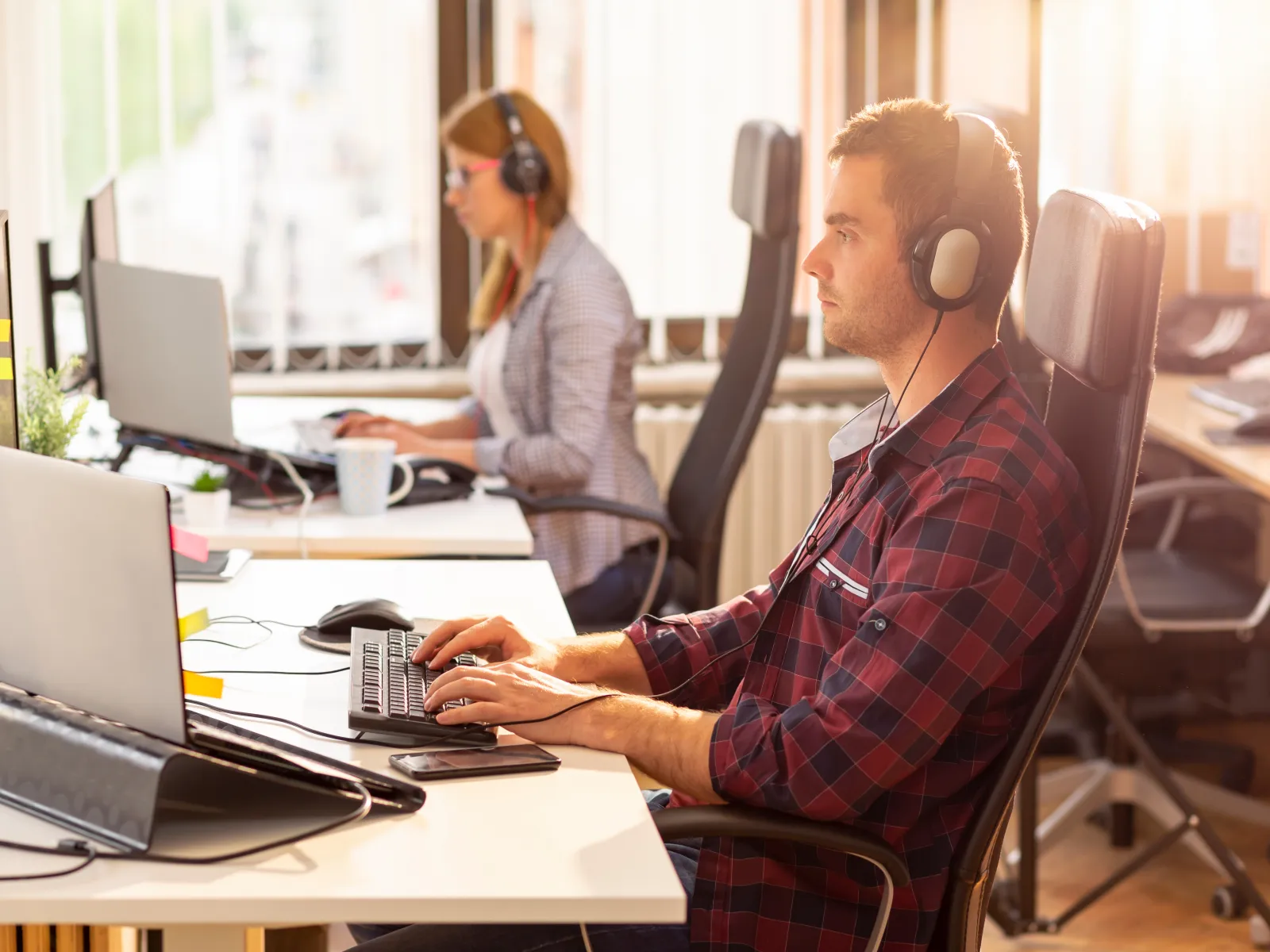 a man and a woman wearing headphones and sitting at a desk