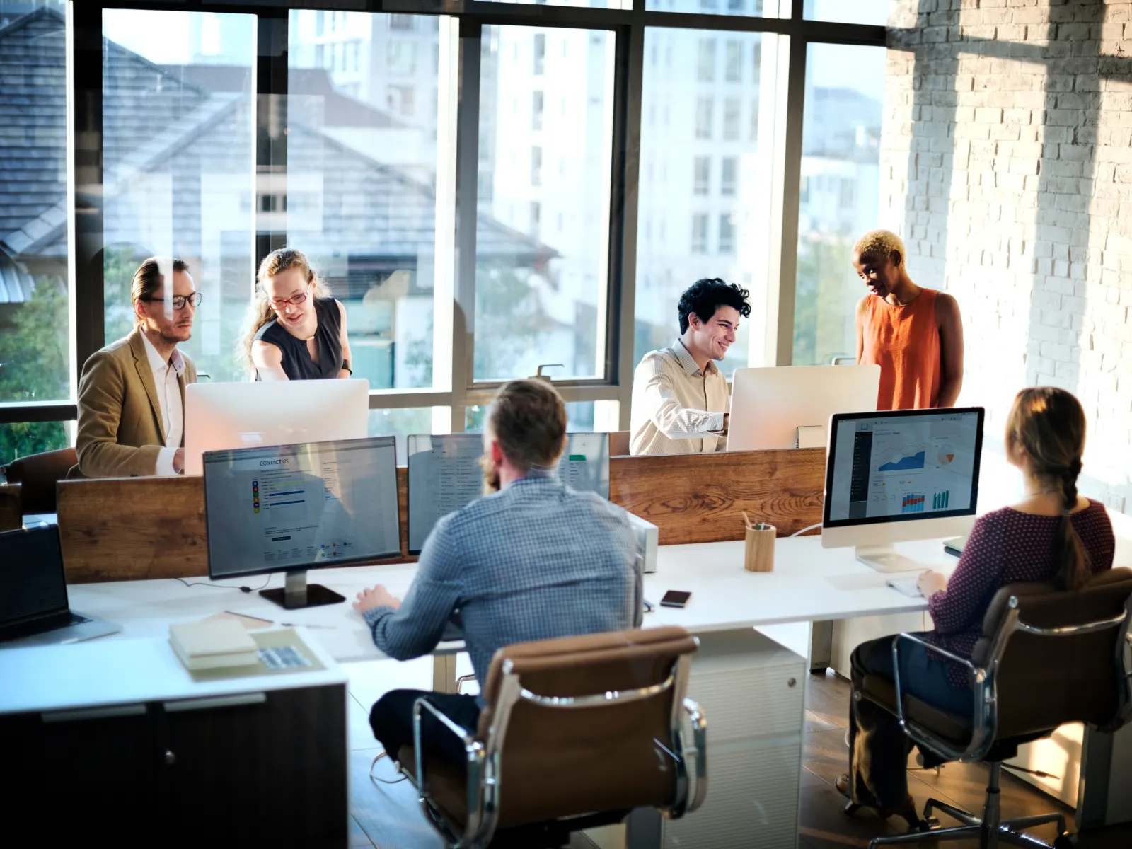 a group of people sitting around a table with computers