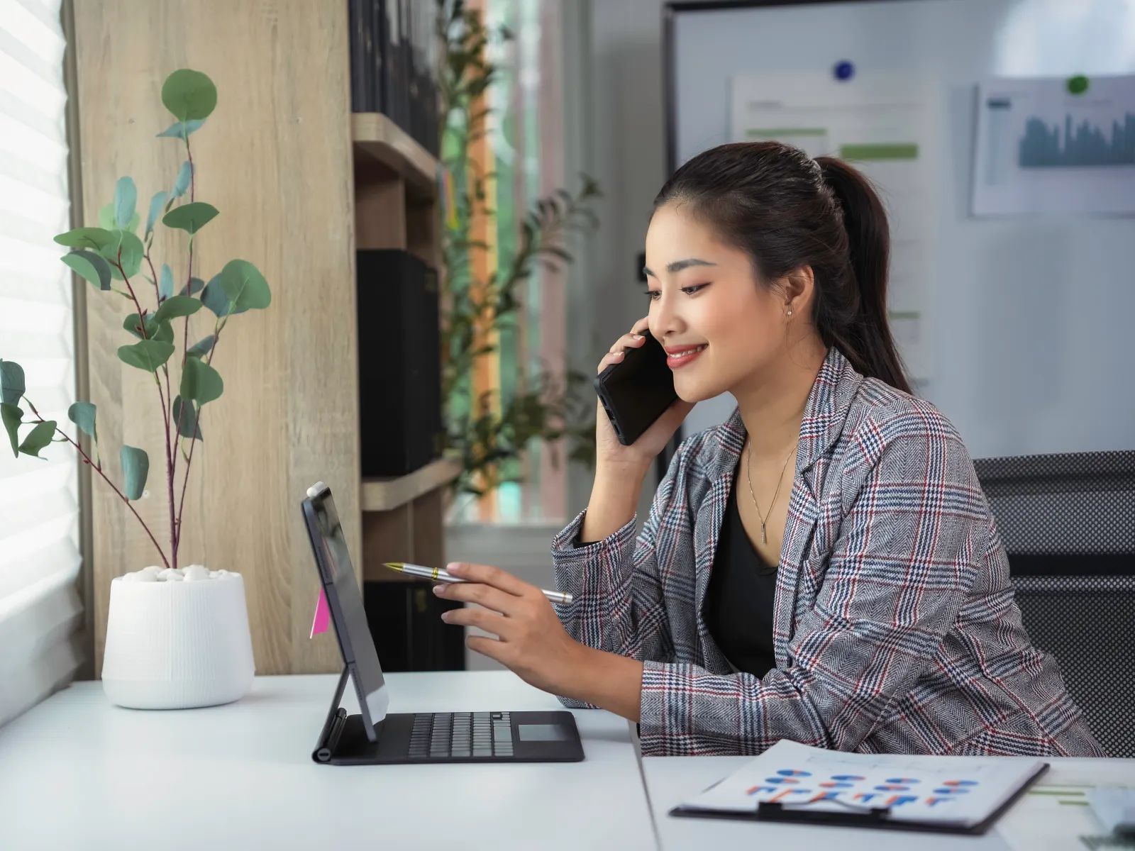 a woman sitting at a table with a laptop and a plant