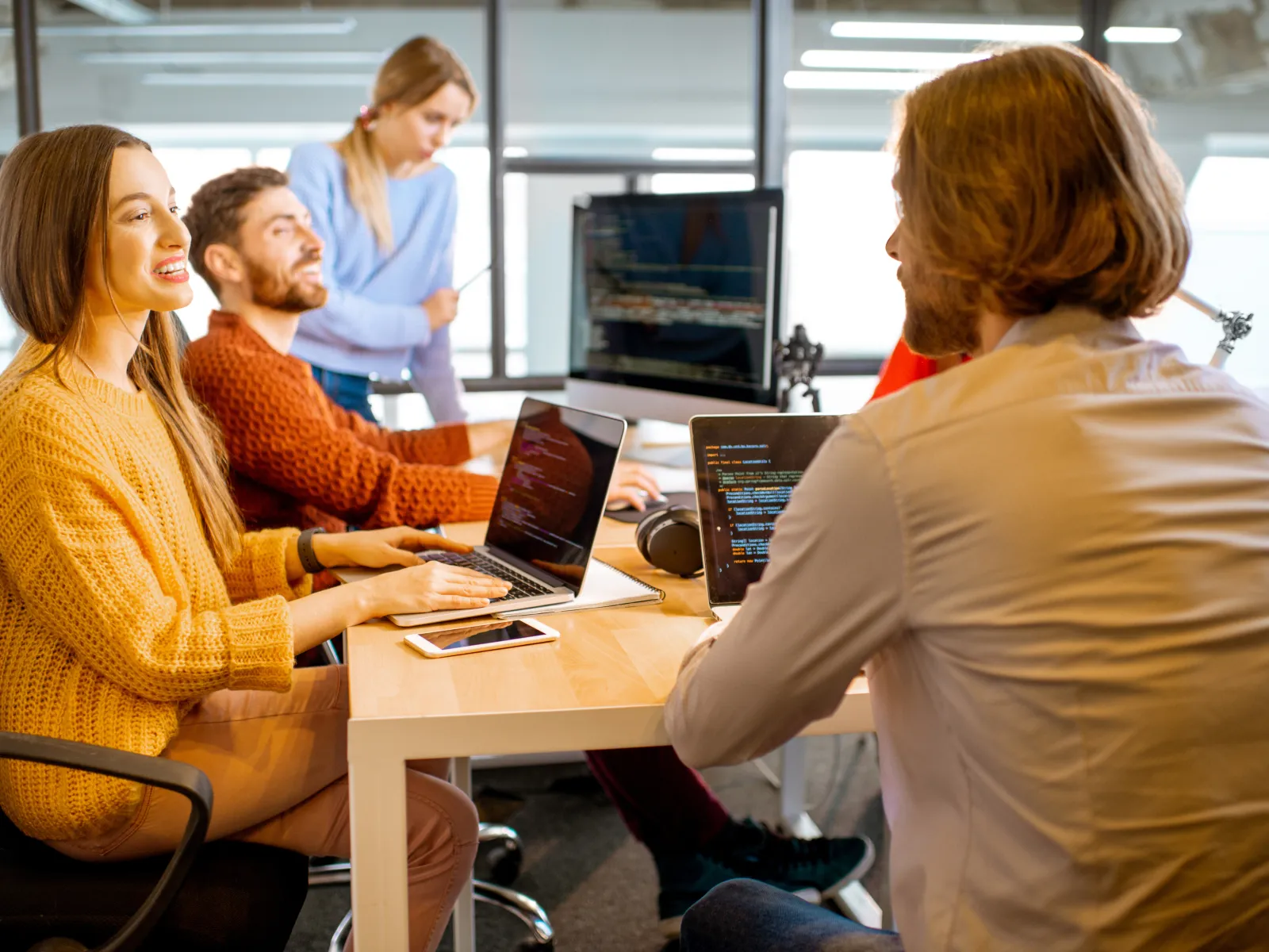 a group of people sitting at a table with laptops