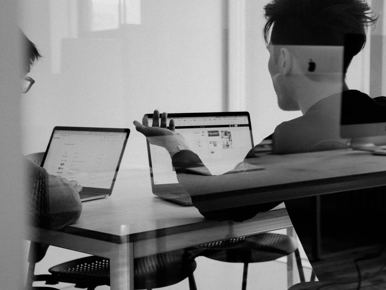 a person sitting at a desk with a laptop and a computer