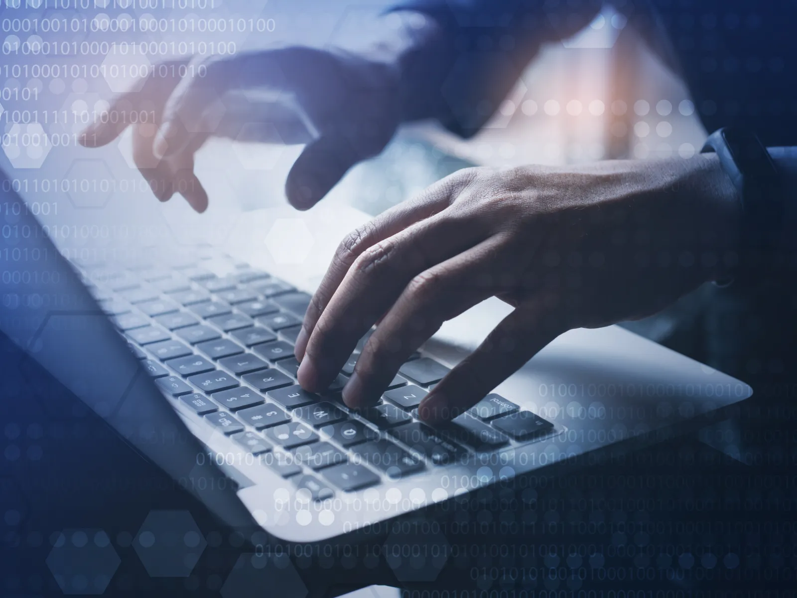Close-up of hands typing on laptop keyboard with digital binary code overlay representing cybersecurity.