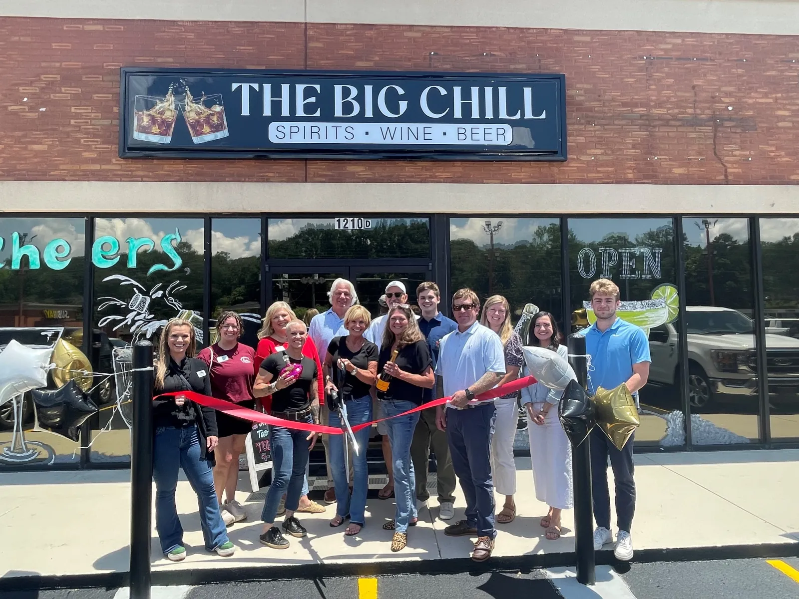 Group of people holding a ribbon cutting ceremony in front of The Big Chill spirits, wine, and beer store