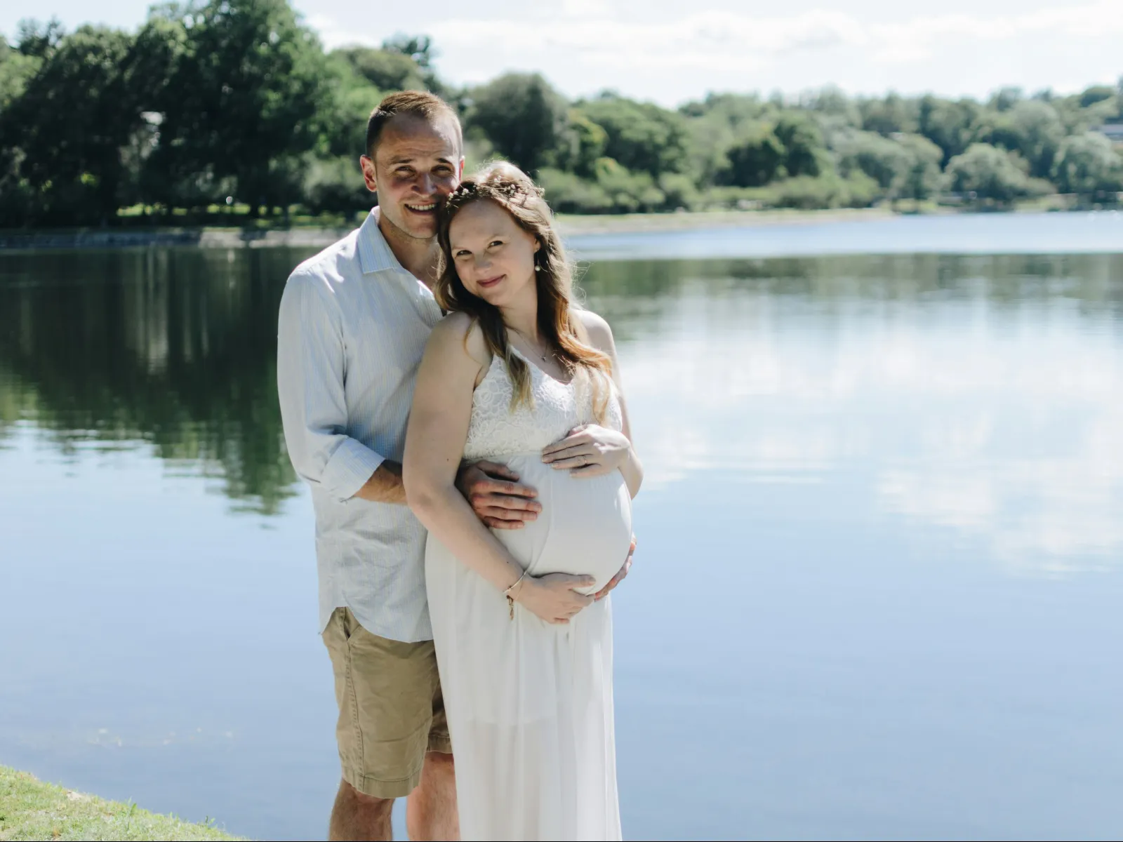 a man and woman posing for a picture next to a body of water