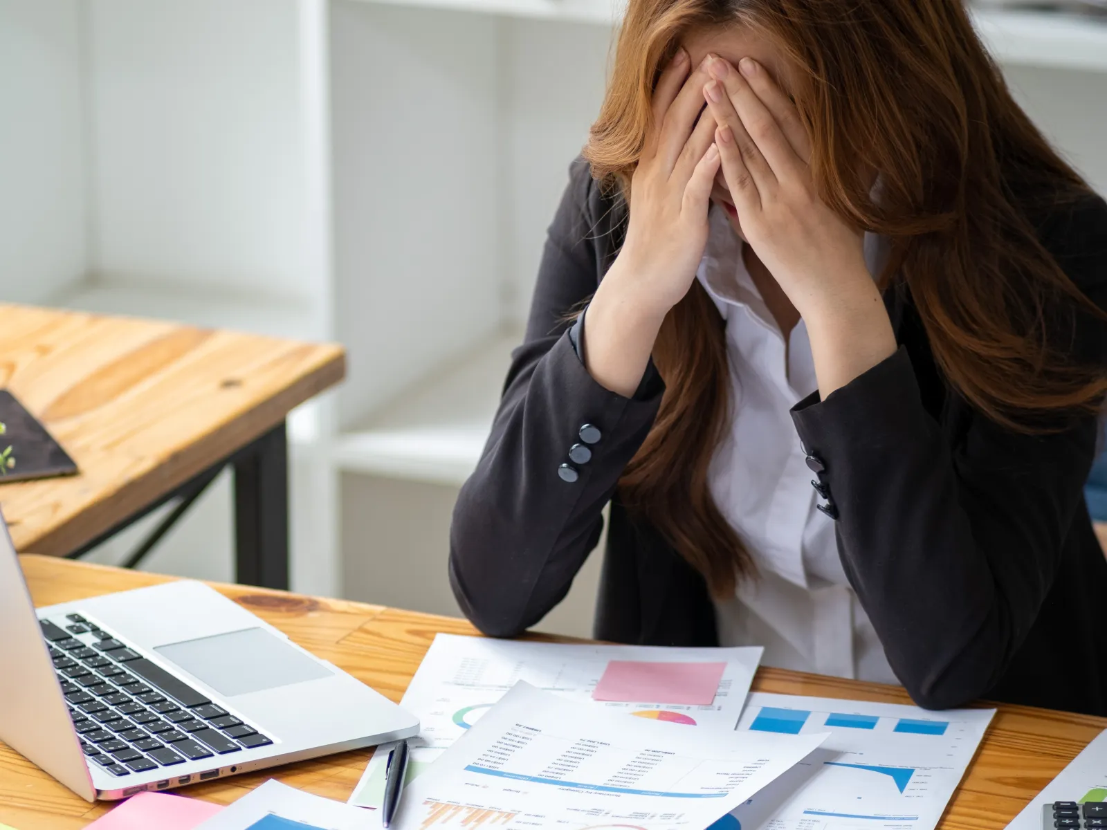 a woman sitting at a desk with her hand on her face