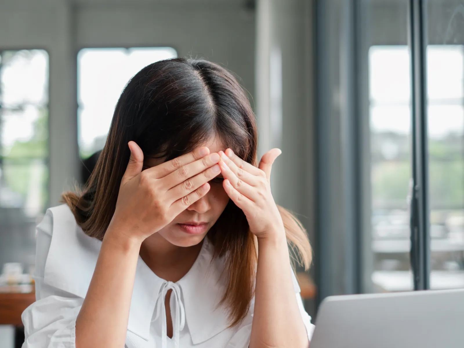 a woman sitting at a table with her hands on her face