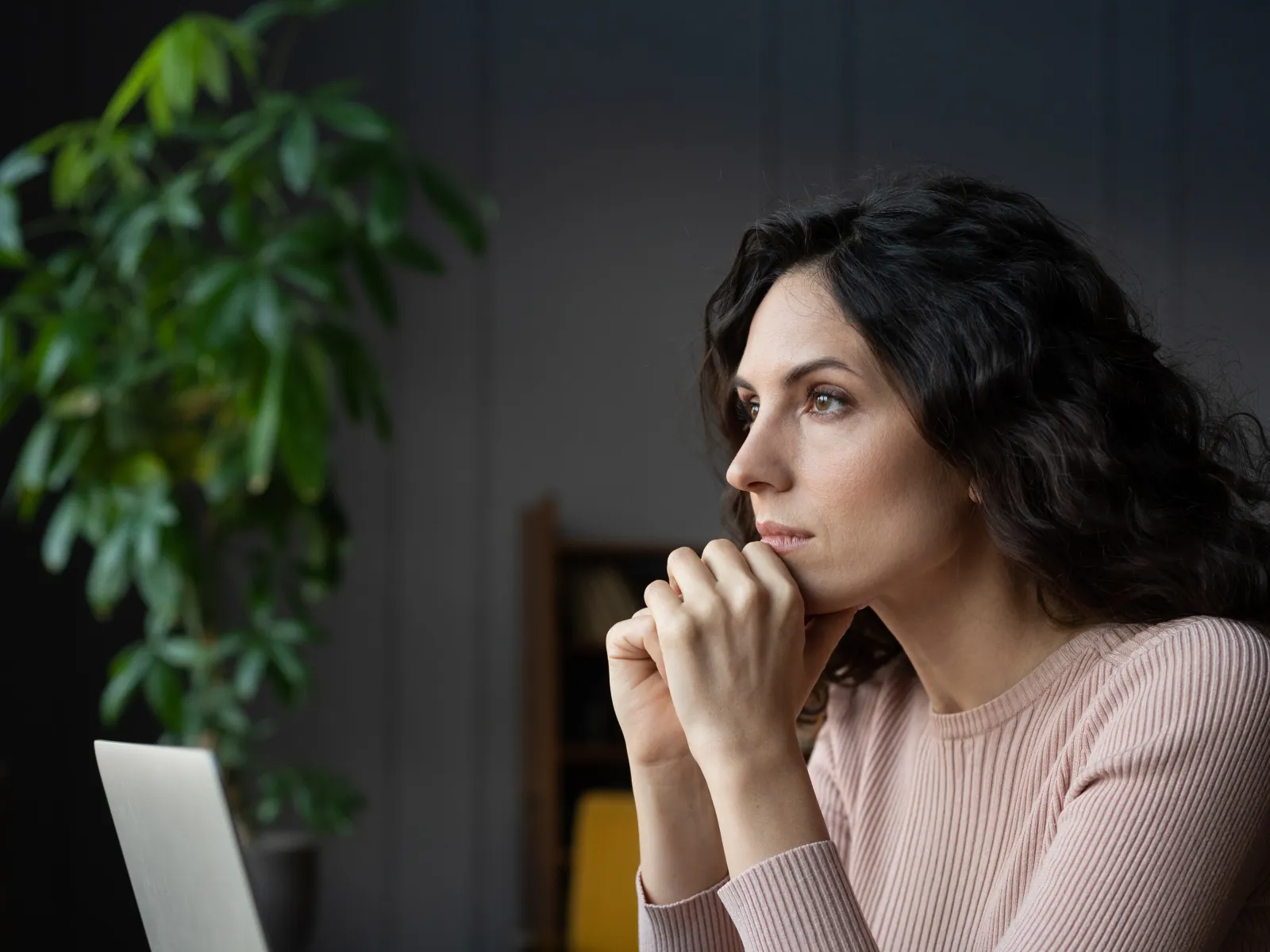 a woman sitting at a table with a laptop and a glass of water