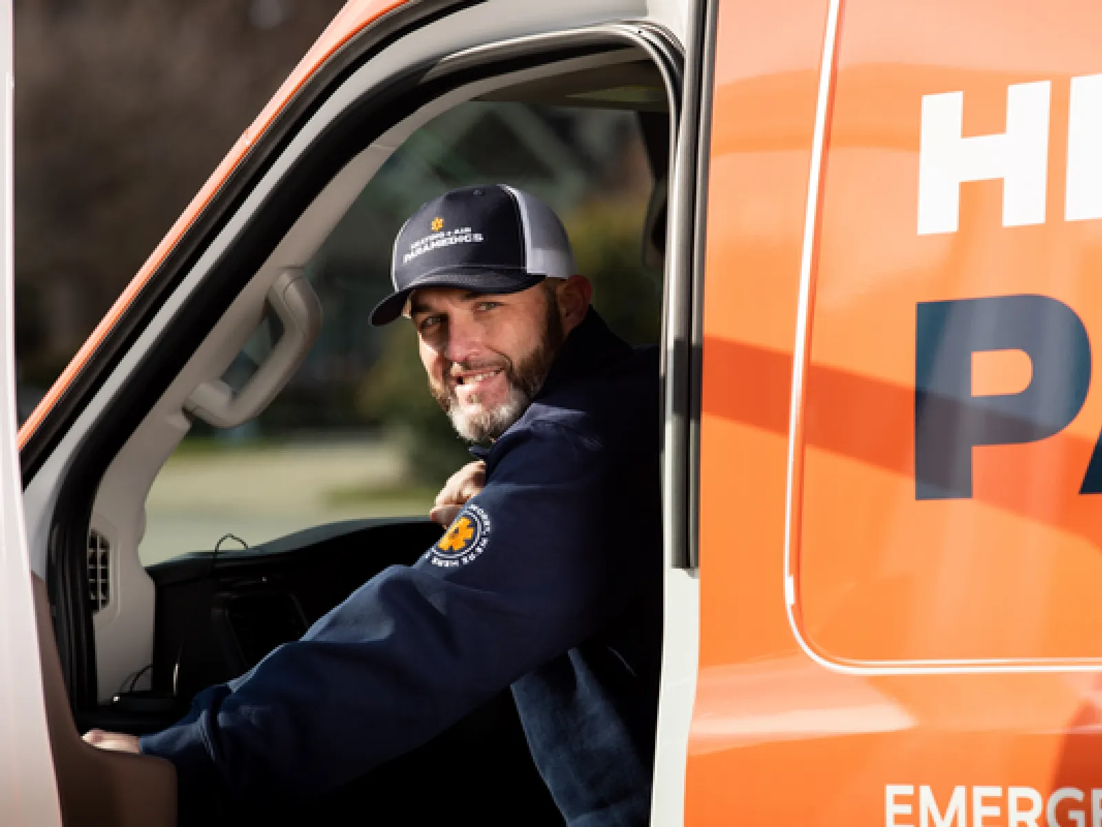 Technician in uniform holding brochures outside a house promoting heating and air paramedic services.