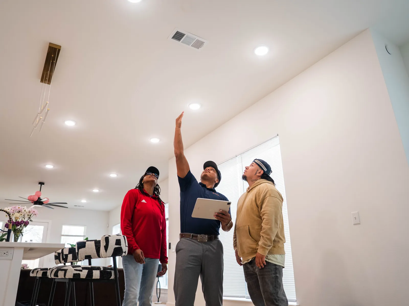 Home inspector checking ceiling and lights in a modern living room with homeowners observing.
