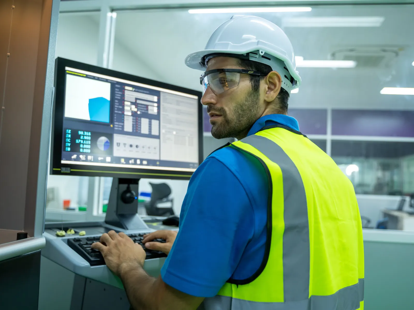 a man wearing a hard hat and working on a computer