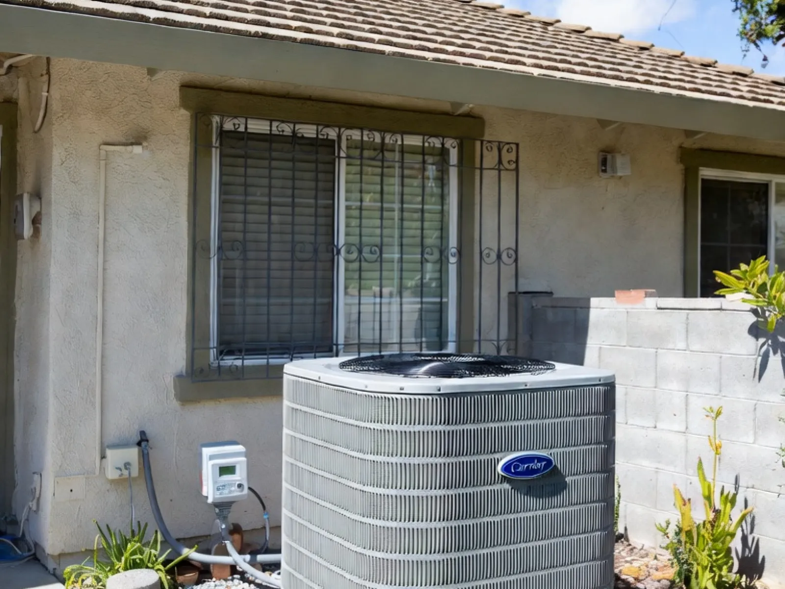 Carrier air conditioning unit installed outside a house next to a window on a concrete slab.