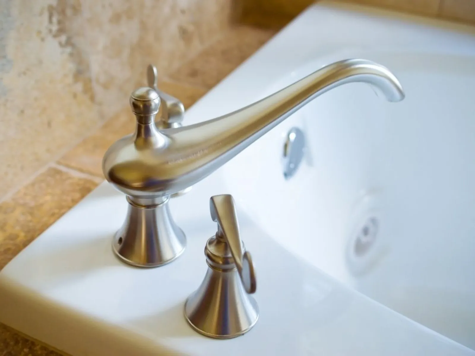 Plumber fixing kitchen sink pipes with adjustable wrench under the counter, hands working on fittings.