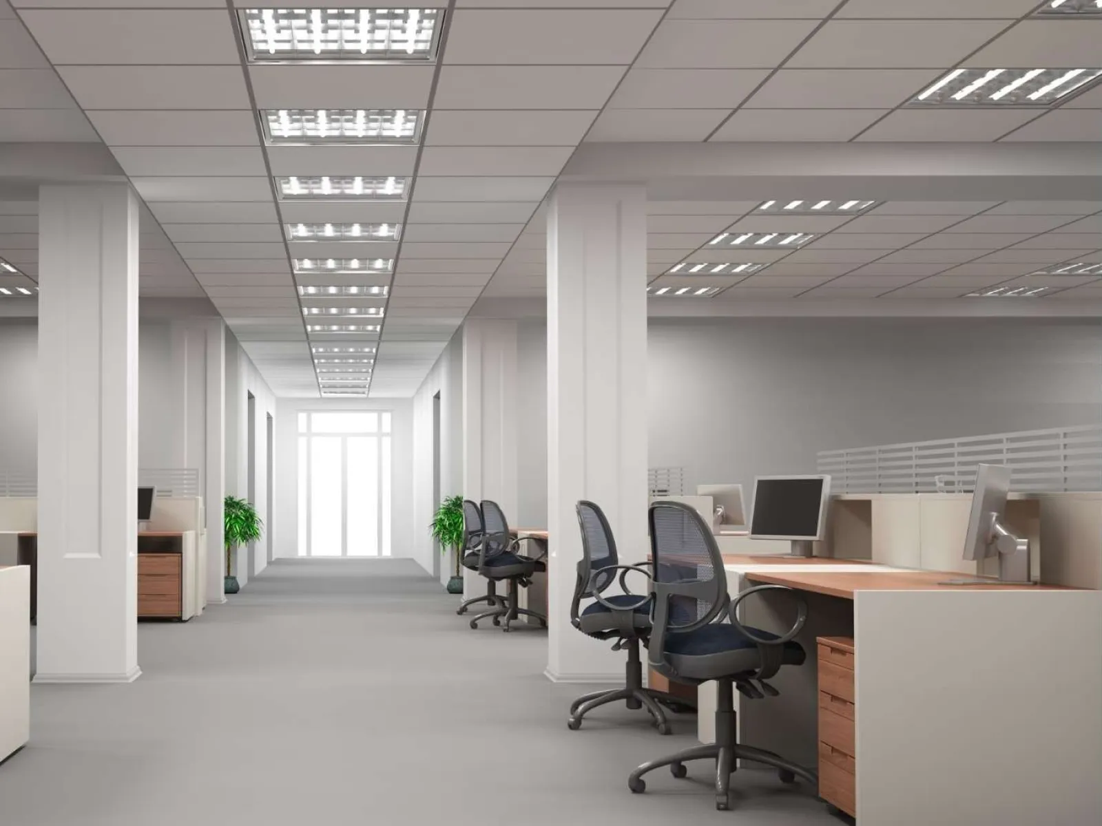 Modern empty open-plan office with desks, chairs, computers, and bright overhead lighting in a clean workspace
