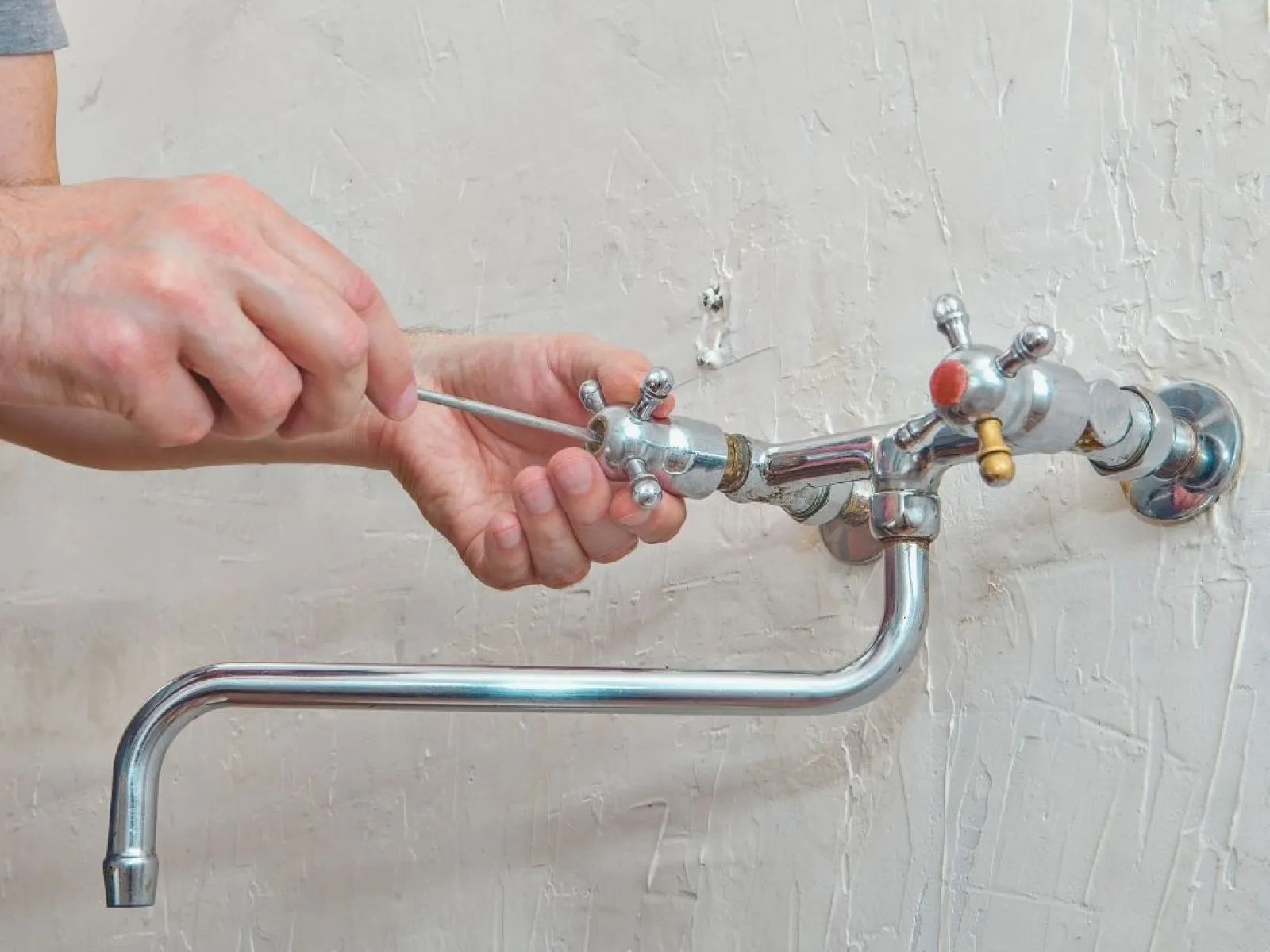 Close-up of a gloved hand holding a corroded metal valve with a blue handle against a white background