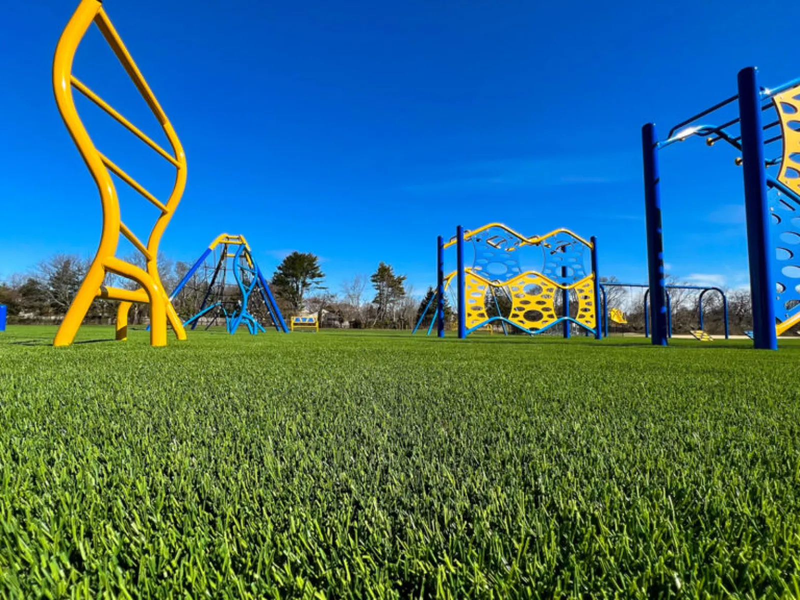 a grassy field with a playground in the background