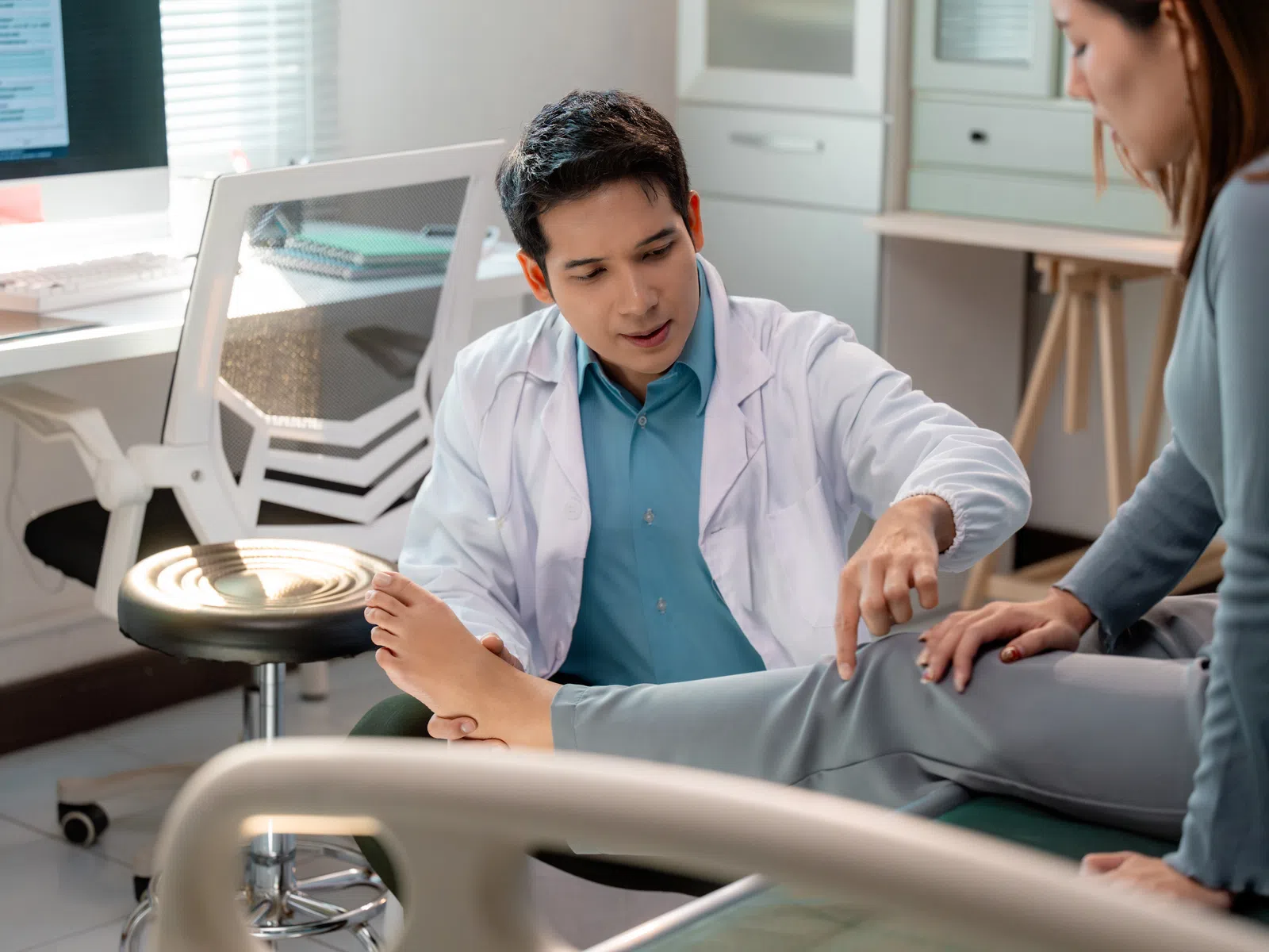 Doctor examining a patient's leg in a medical office during a consultation.