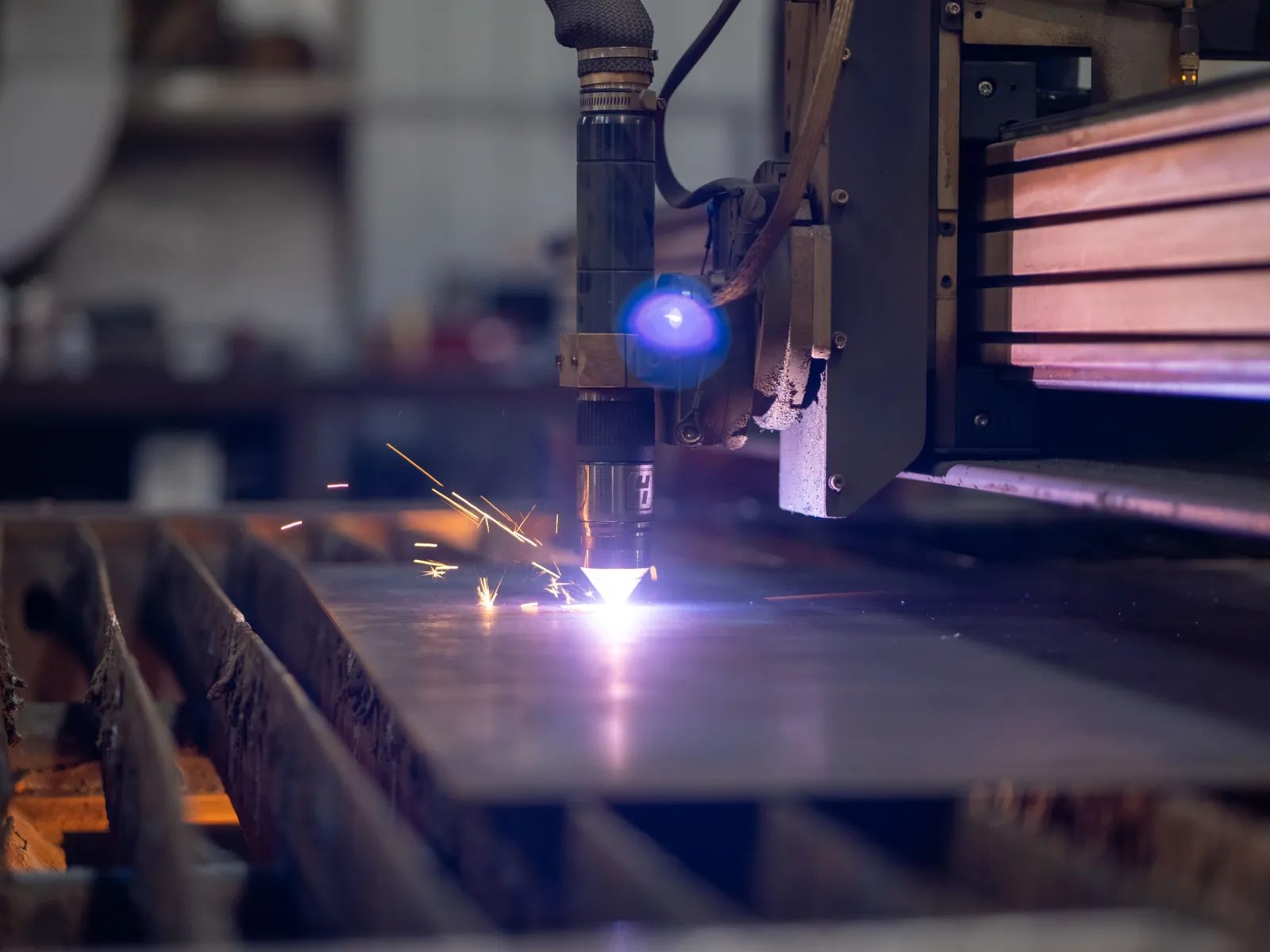 Close-up of a CNC plasma cutting machine cutting metal with bright sparks in an industrial workshop.