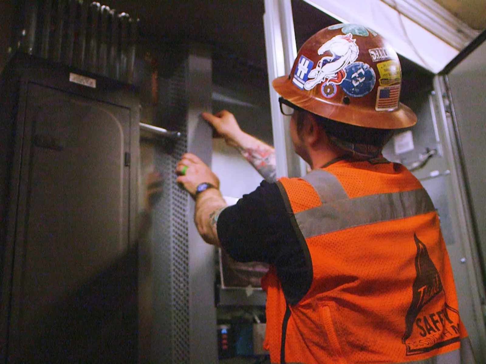 a person in an orange vest looking at a computer