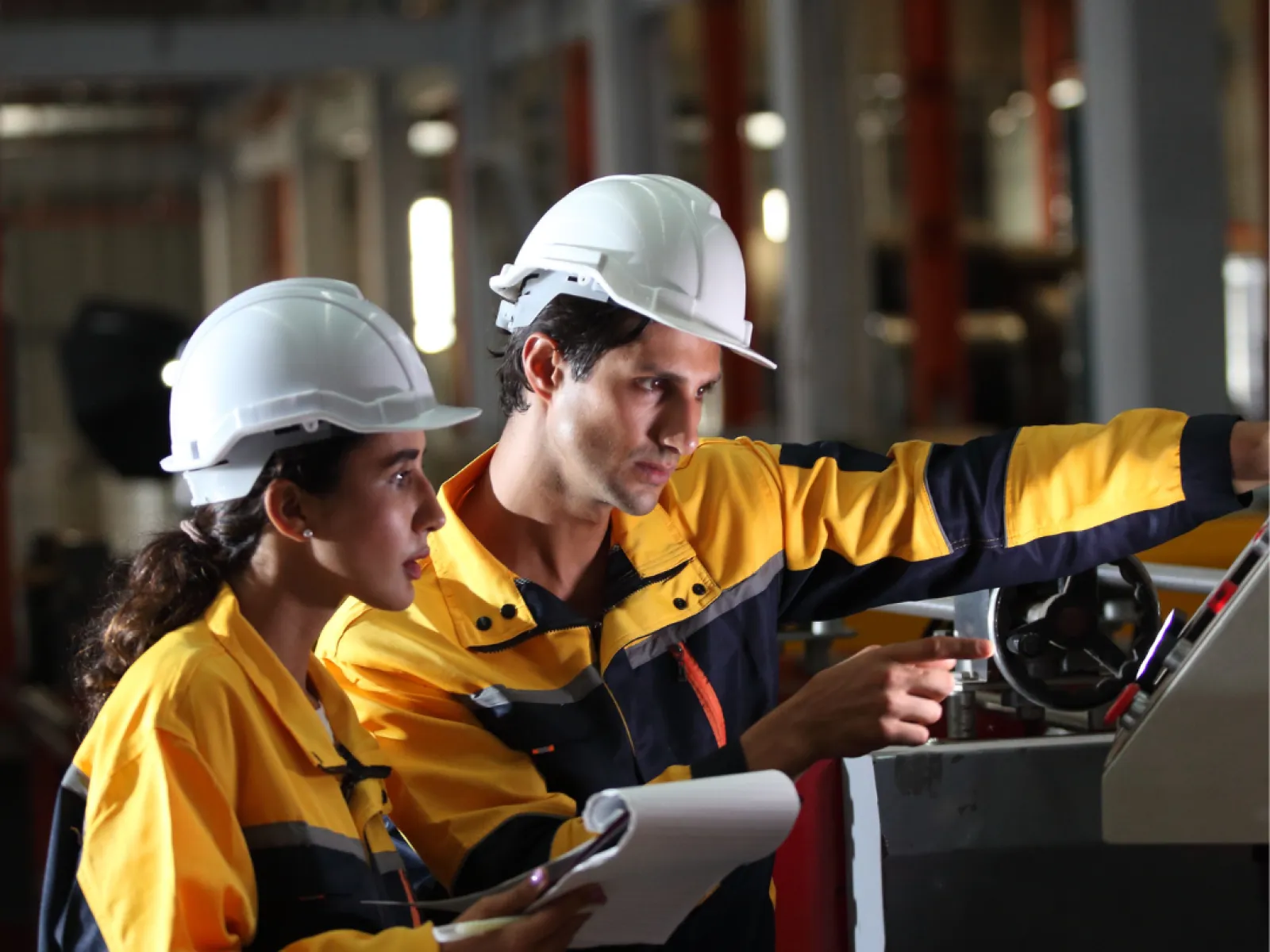 a few workers in hardhats looking at a tablet