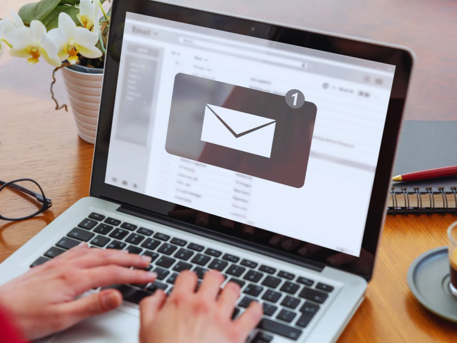 Person typing on laptop showing new email notification with one unread message on screen.
