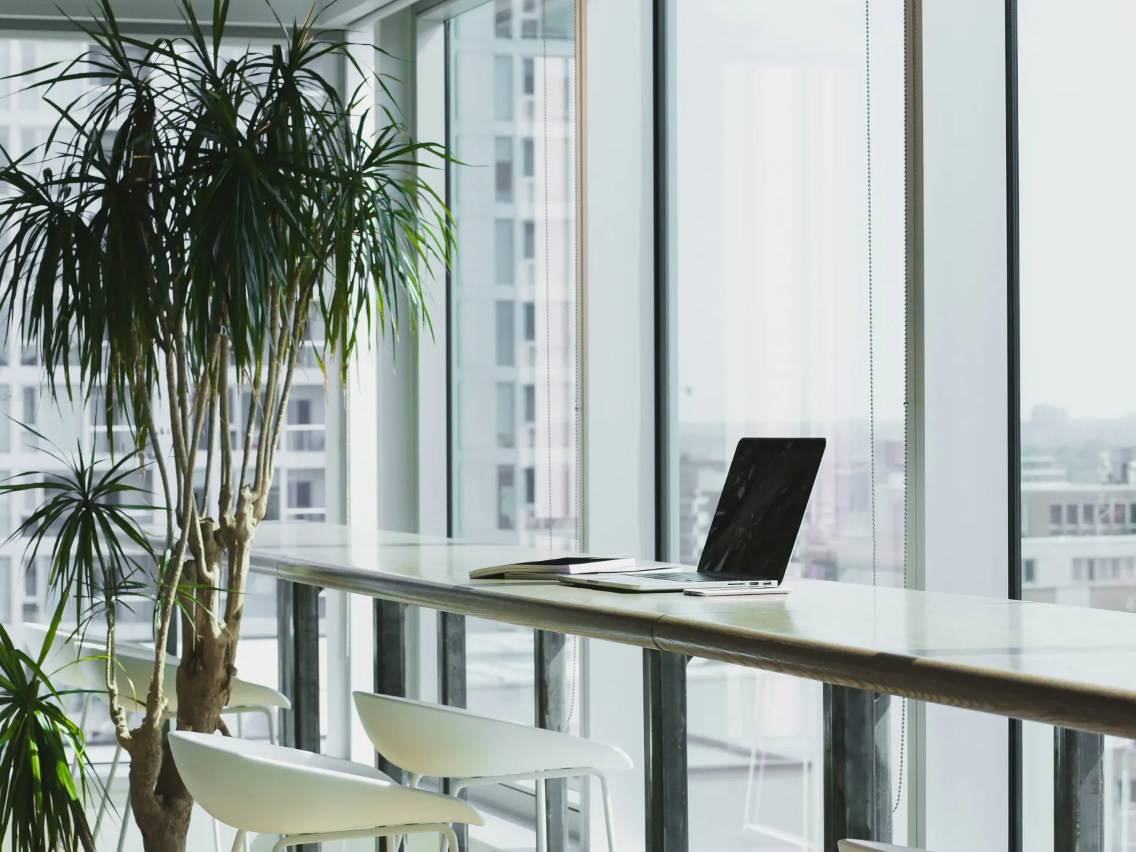 a table with a laptop and chairs by a window