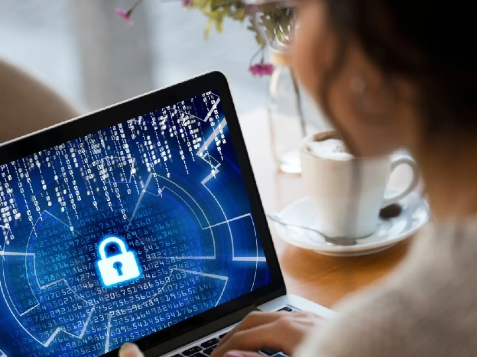 Person using laptop with digital lock symbol and data streams representing cybersecurity protection.