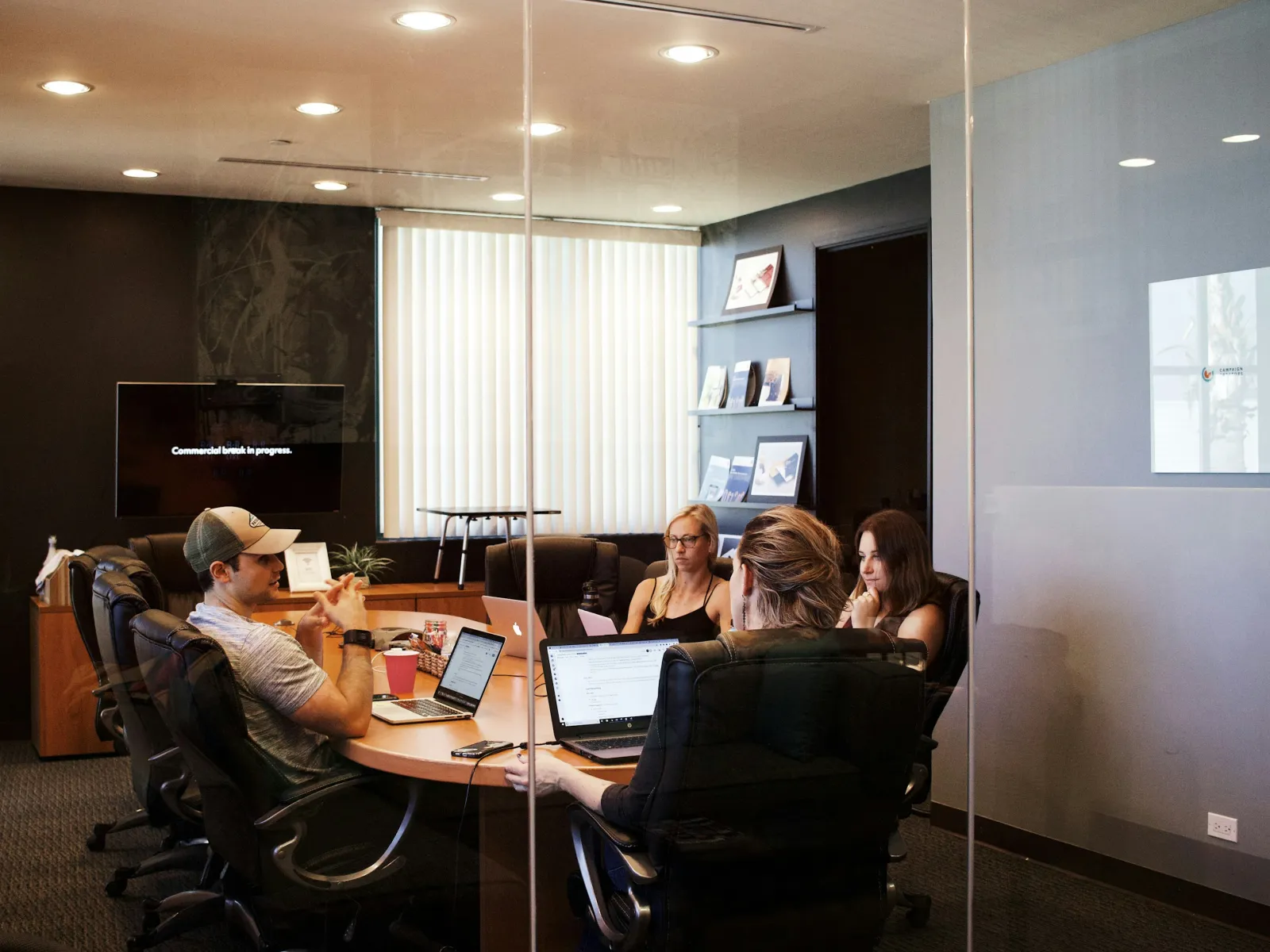a group of people sitting around a table with laptops