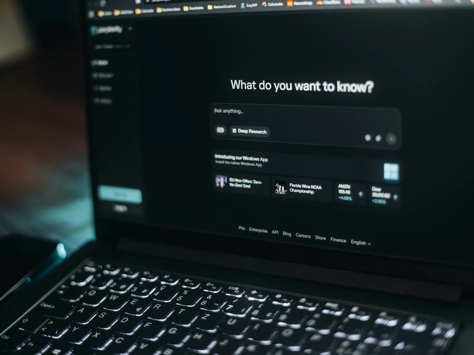 Laptop screen displaying a dark-themed AI research interface with illuminated keyboard keys.