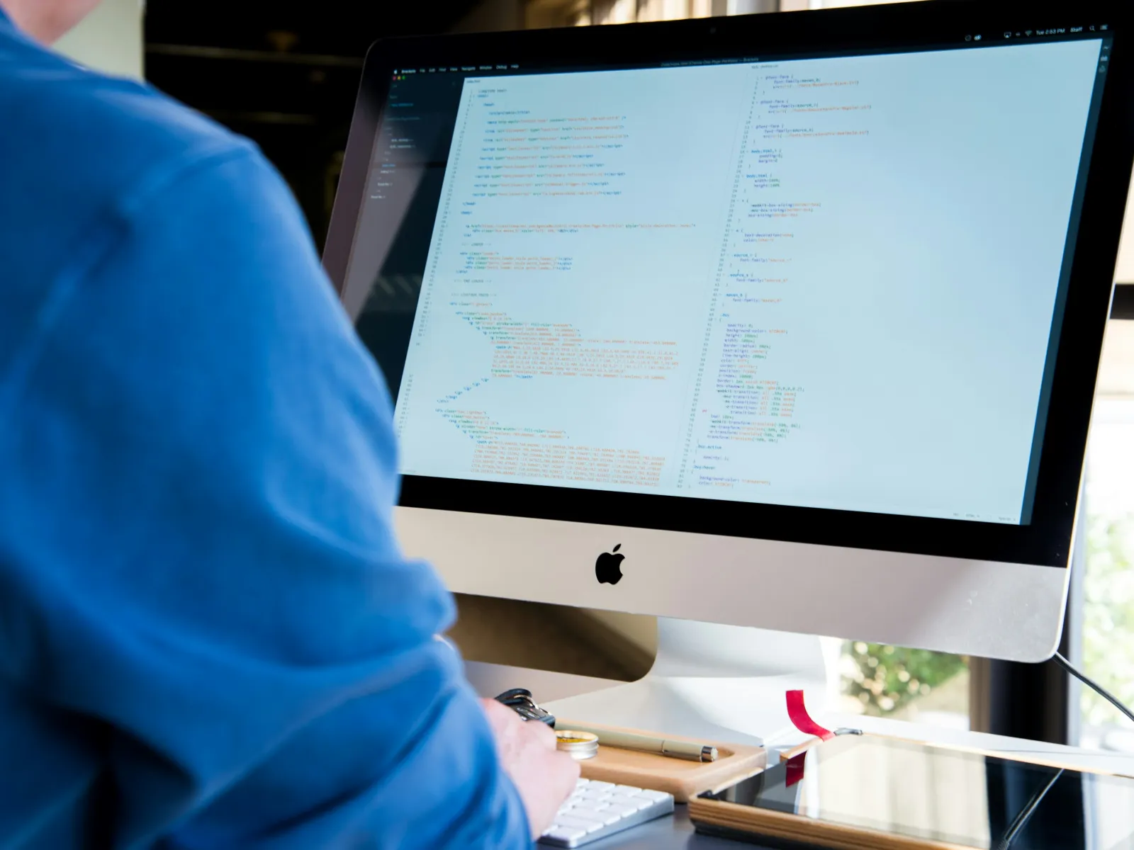 a person in blue scrubs looking at a computer screen