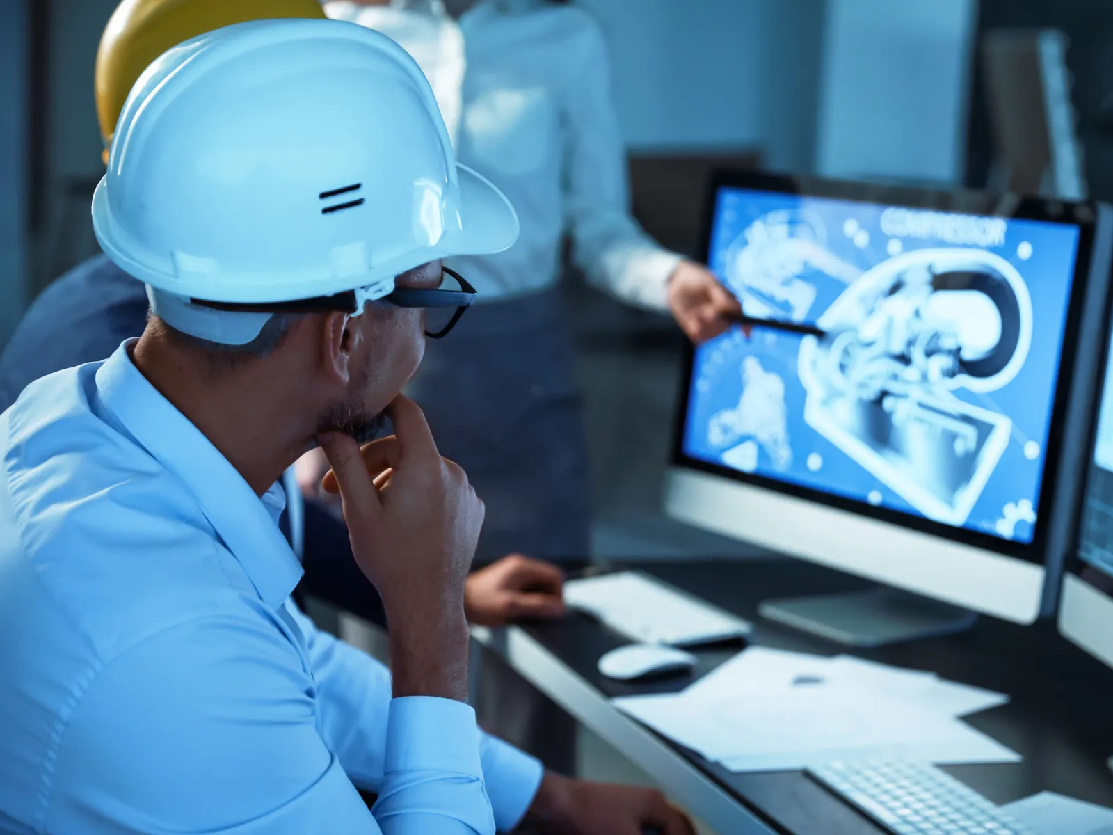 a person wearing a hard hat and looking at a computer screen