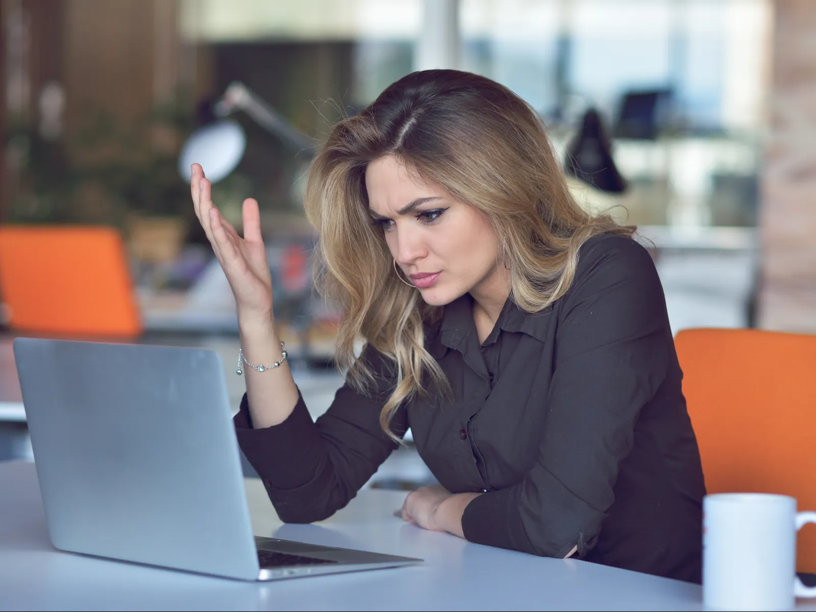 a woman sitting at a table with a laptop and a mug