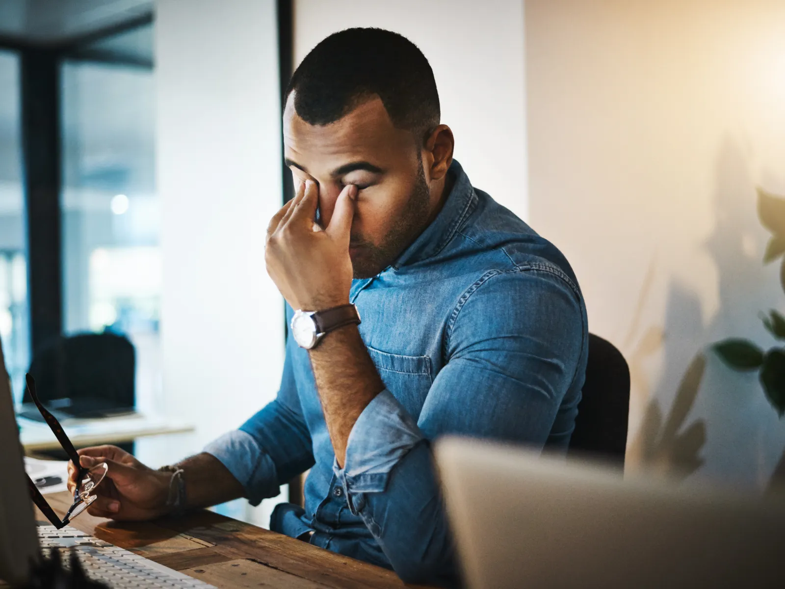 a man sitting at a desk with his hand on his face