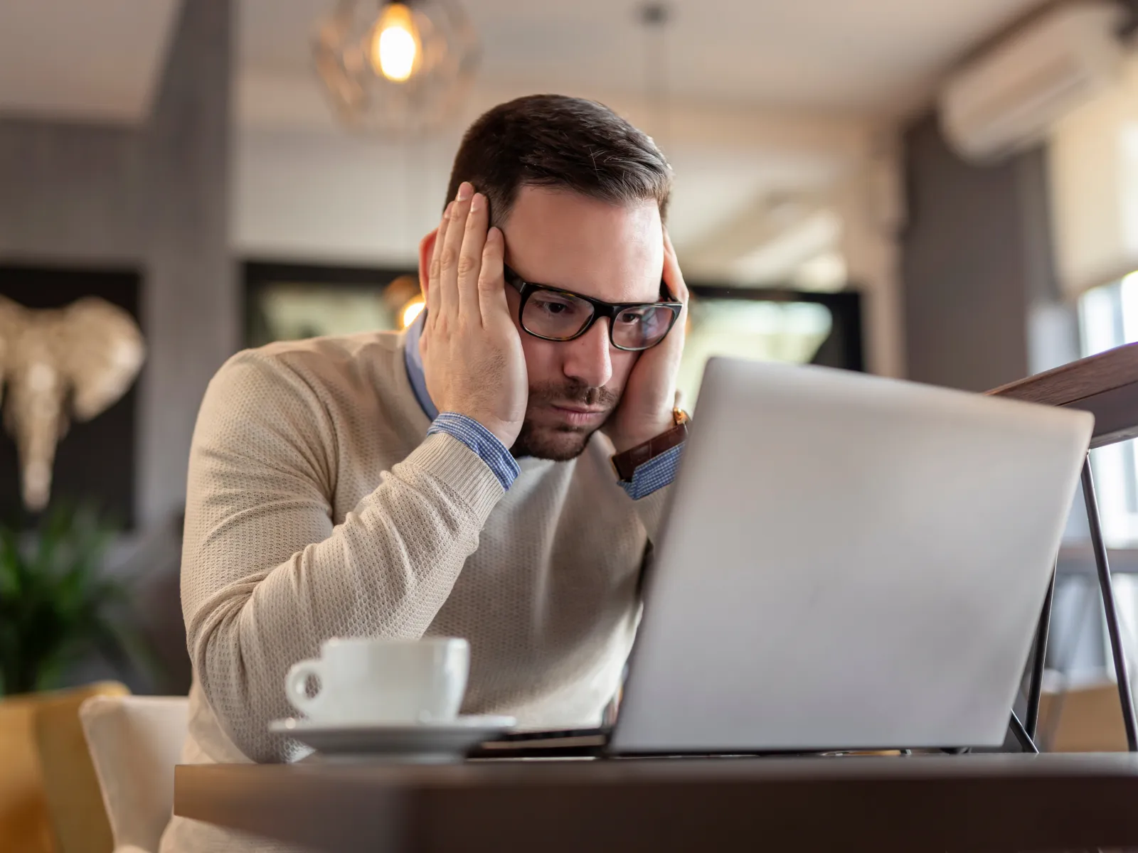 a person with the head in the hands looking at a laptop
