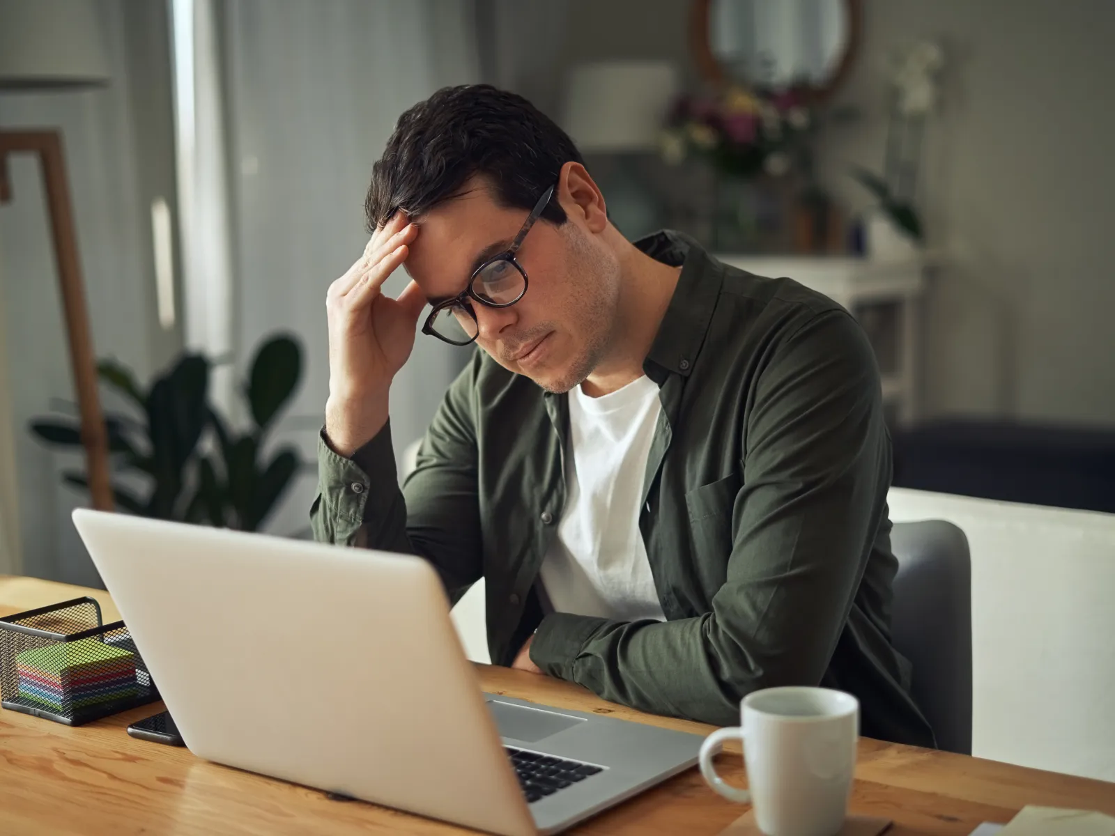 a person sitting at a table with a laptop and a coffee cup