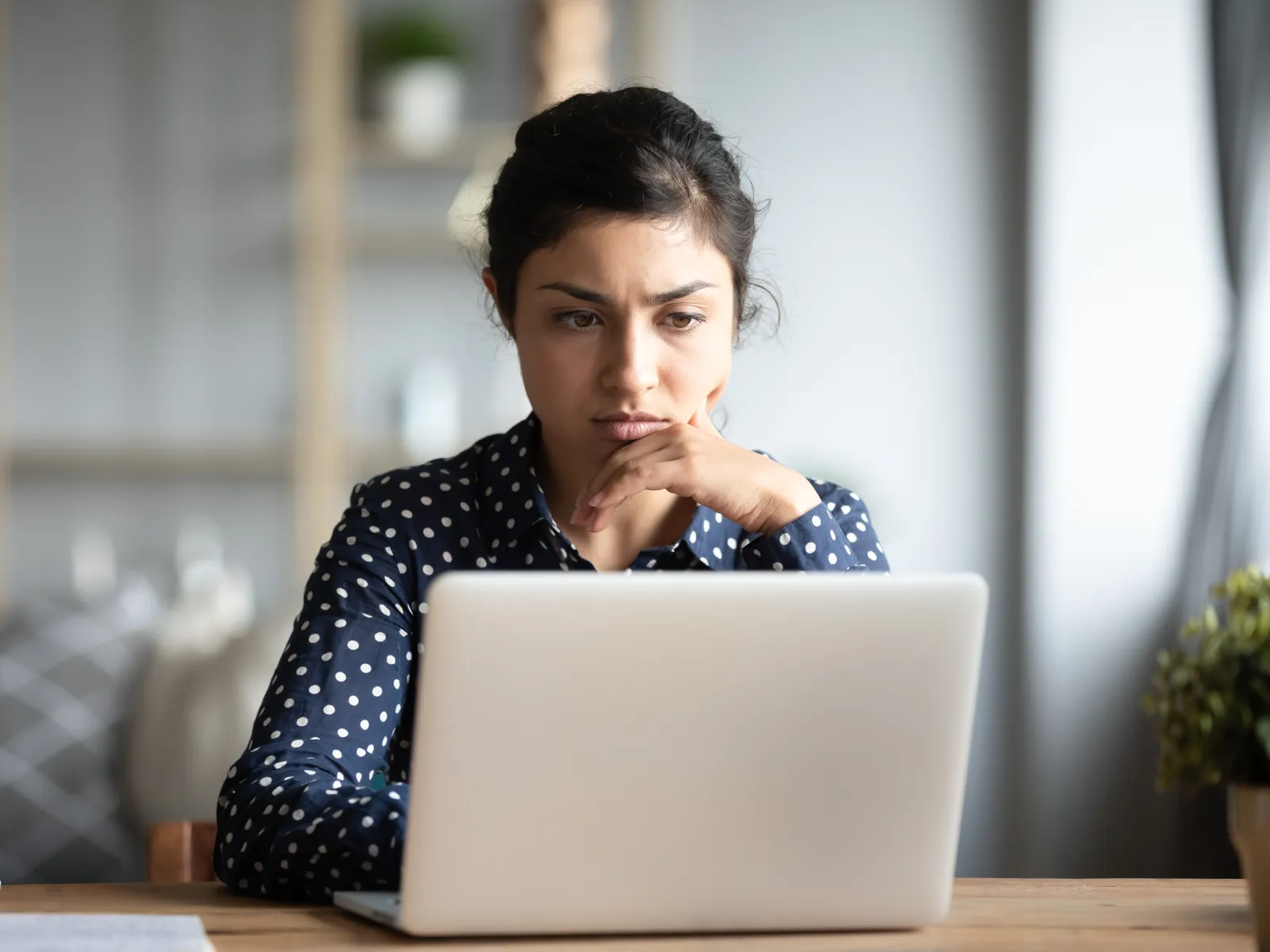 a woman sitting at a table with her hand on her chin