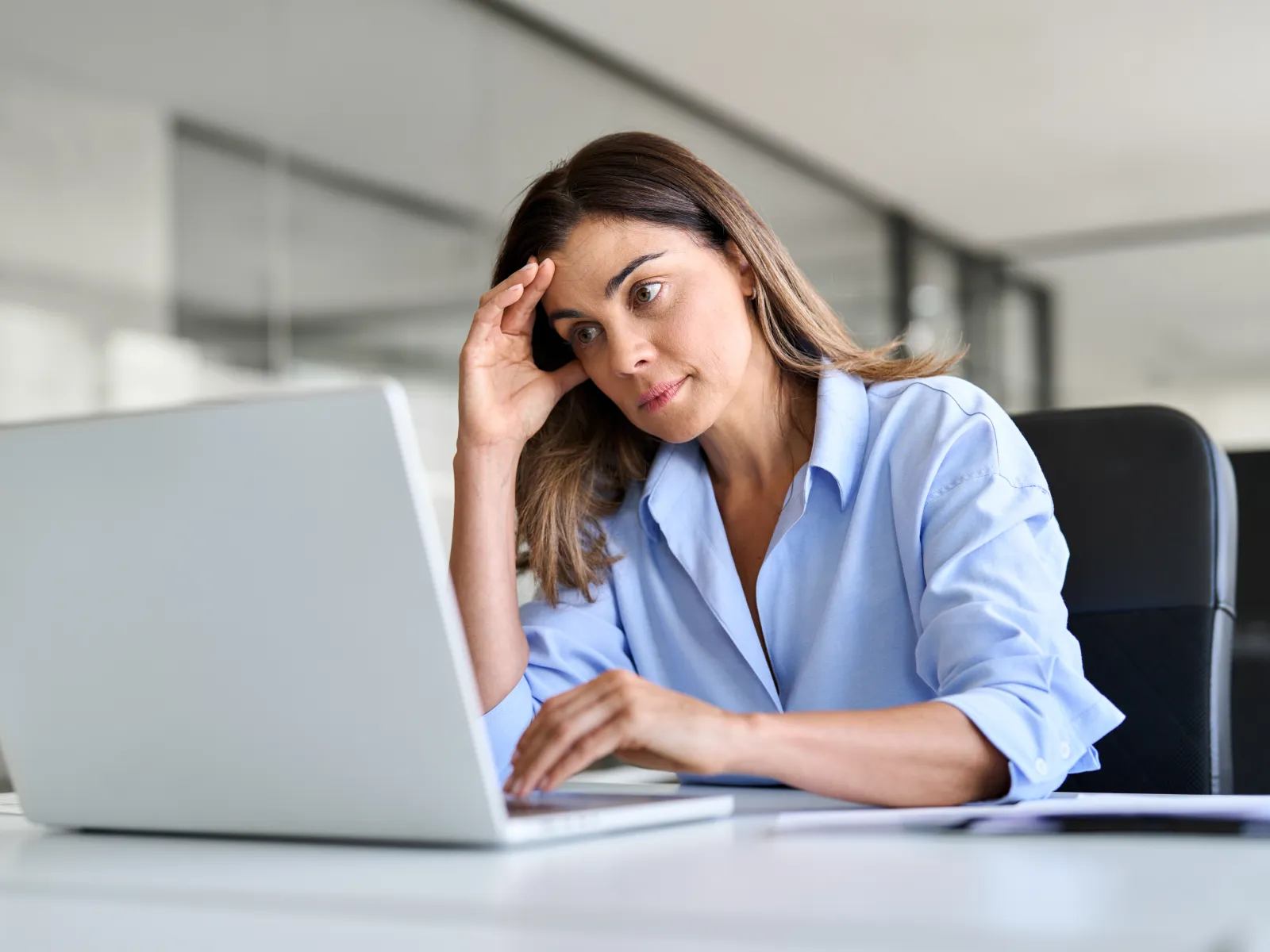 a woman on her phone at a desk with a laptop