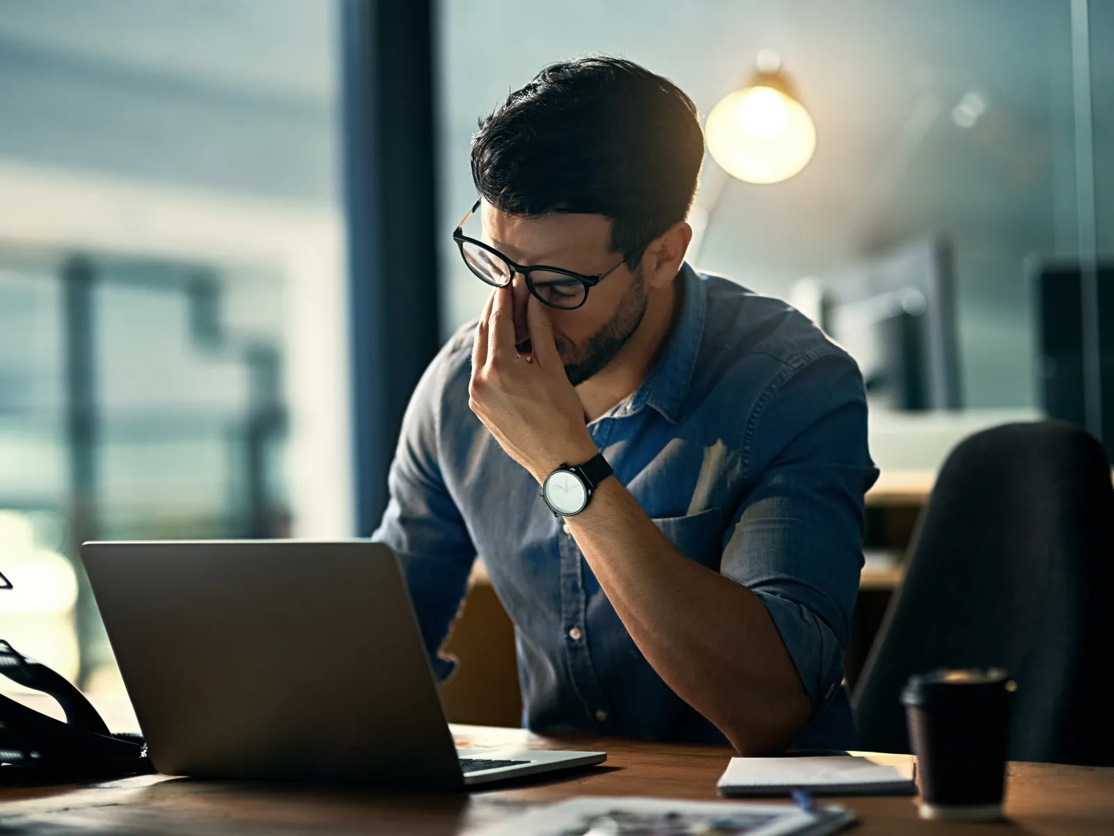 a man sitting at a desk with his hand on his face