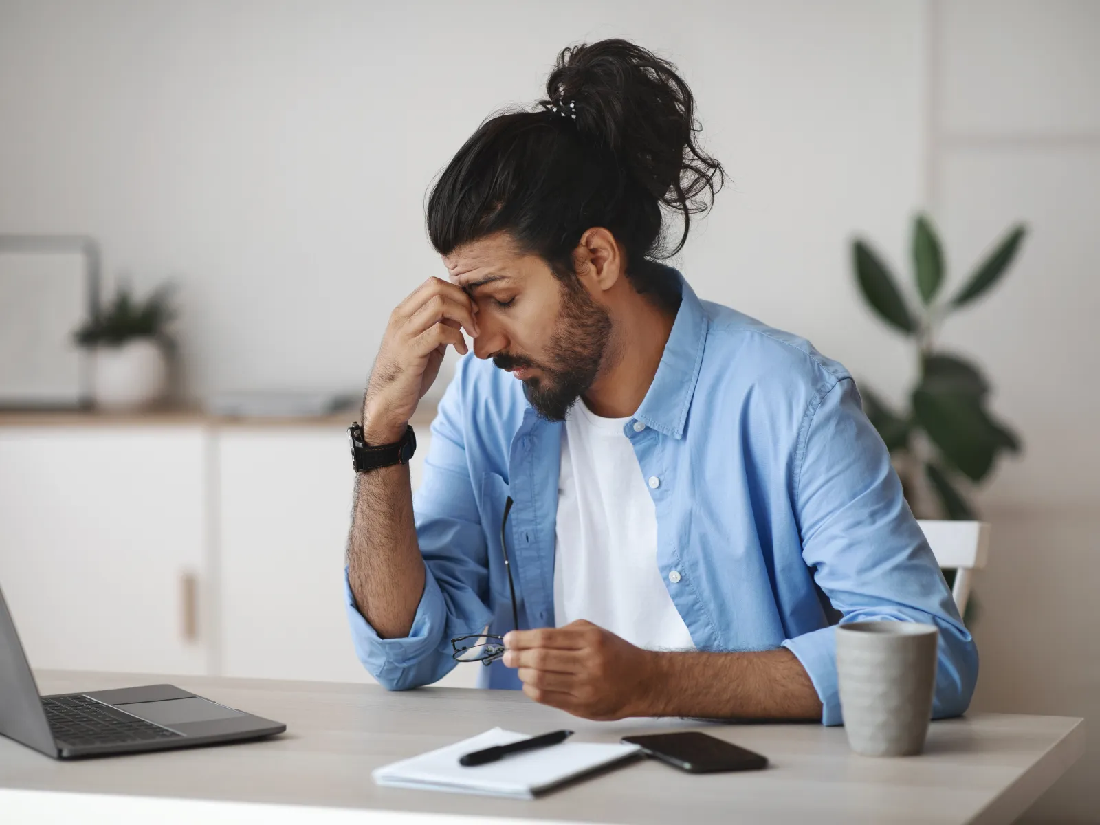 a man sitting at a desk with a laptop and a pen