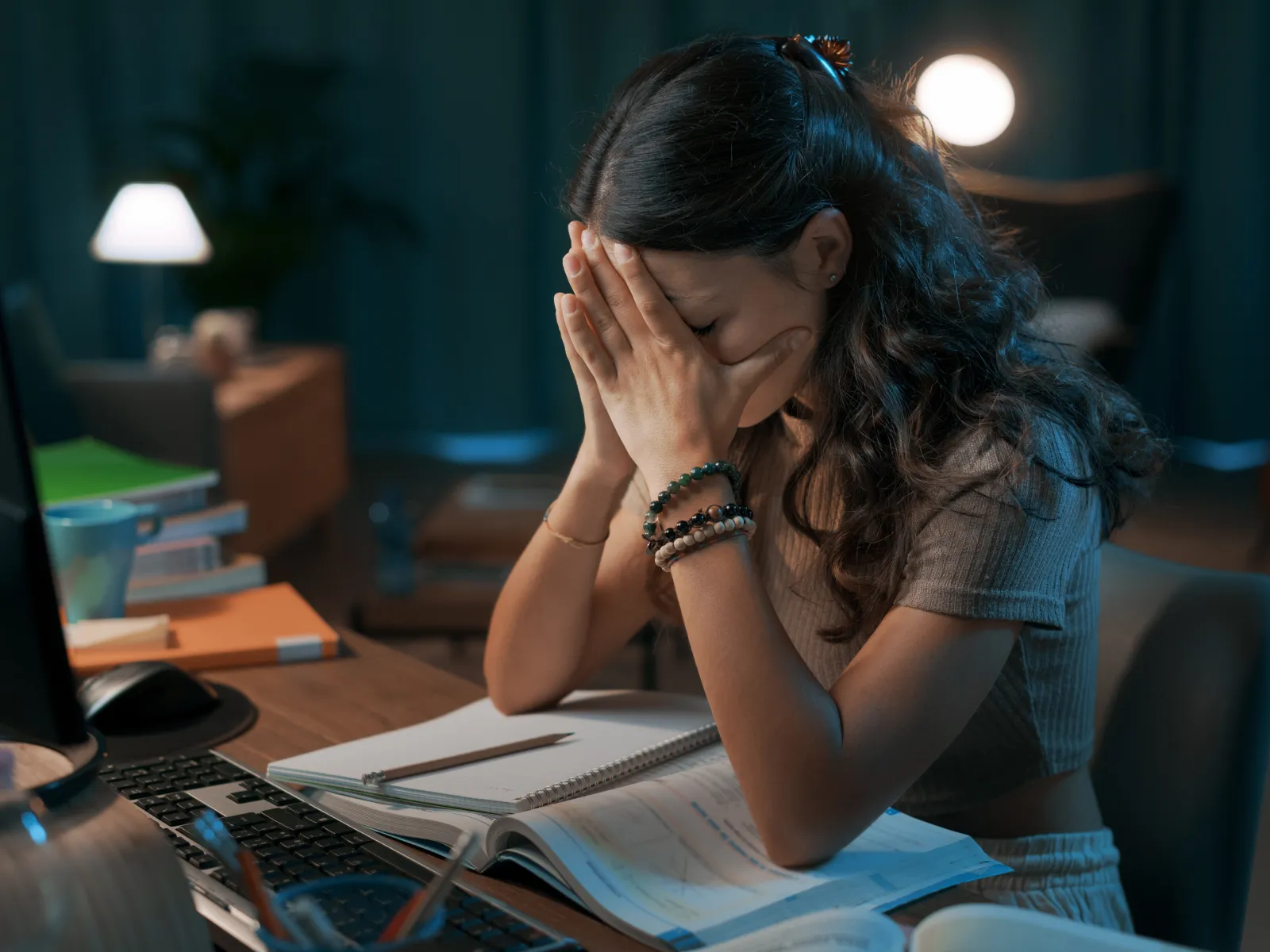a woman sitting at a desk with her hands on her face