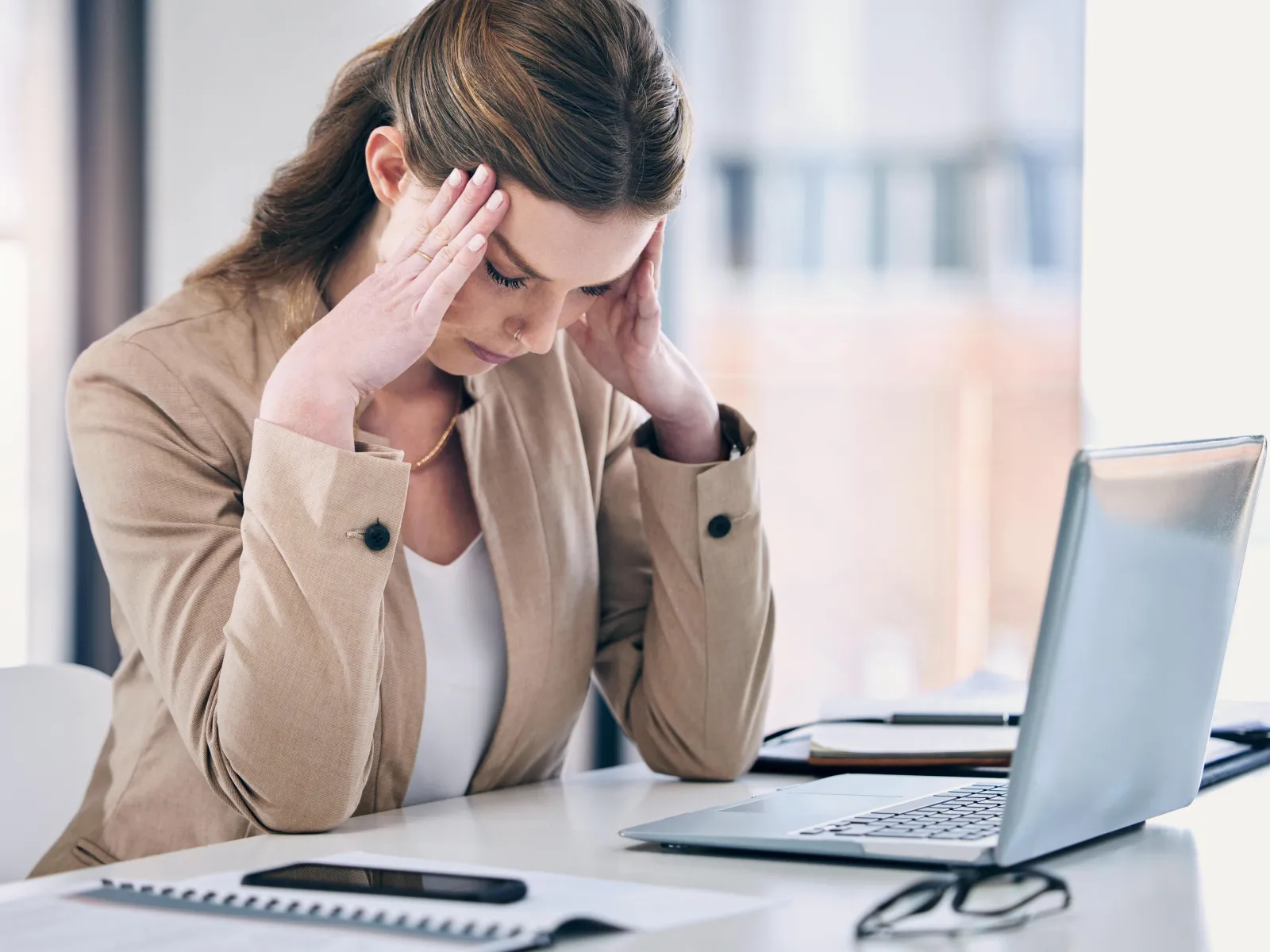 a woman with her hand on her face looking at a laptop