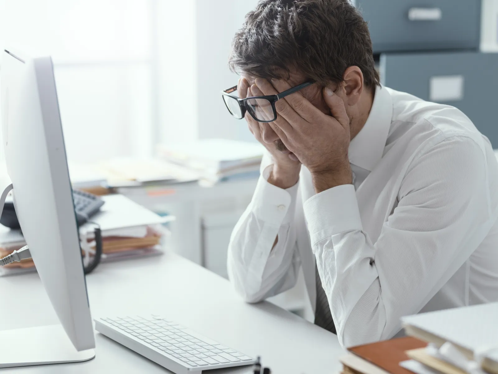 a man sitting at a desk with his hand on his face