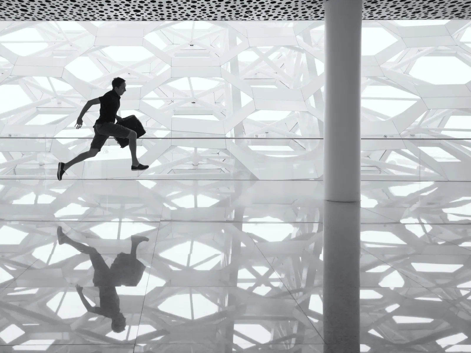 Silhouette of a runner in motion against a modern, geometric architectural backdrop.